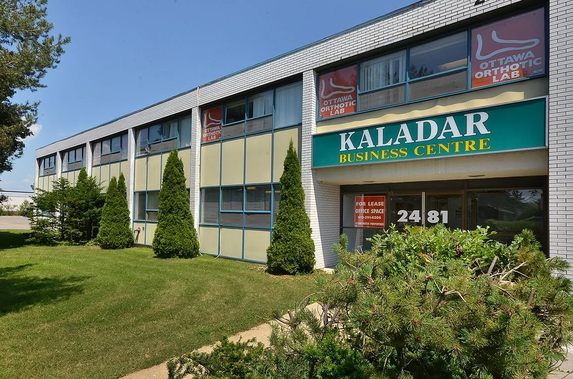 Exterior view of the Kaladar Business Centre with signs for Ottawa Orthotic Lab and a For Lease sign in the window.