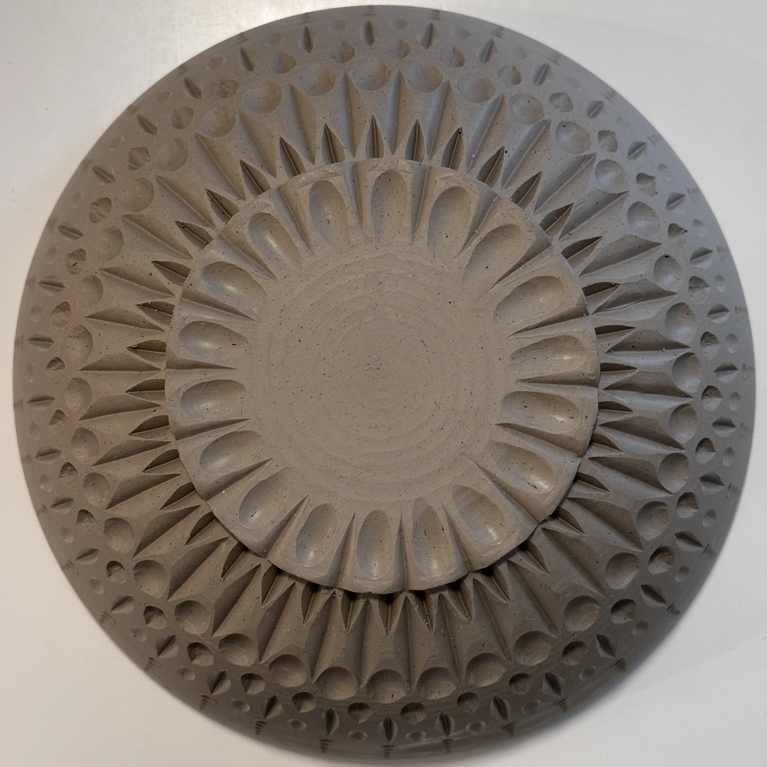 Aerial view of the underside of a hand carved ceramic bowl at the leather-hard stage by Kristen Holub