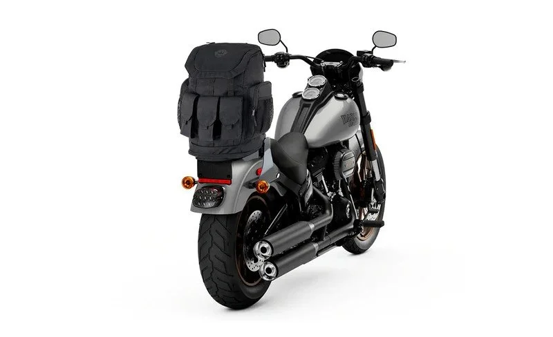 Motorcycle with gray and black finish, equipped with a large black backpack on the rear seat and two exhaust pipes.