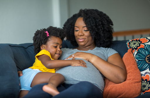 pregnant mother and toddler talking about the new baby on the way.