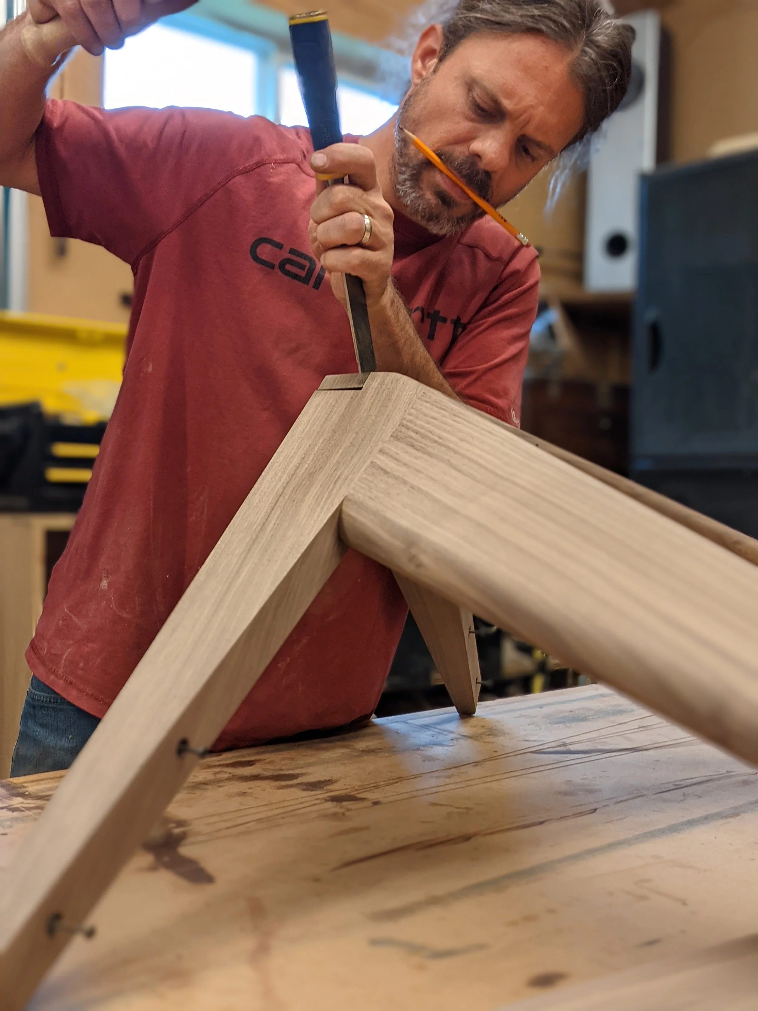 Furnituremaker cutting traditional dovetail joinery in table top apron made of solid walnut