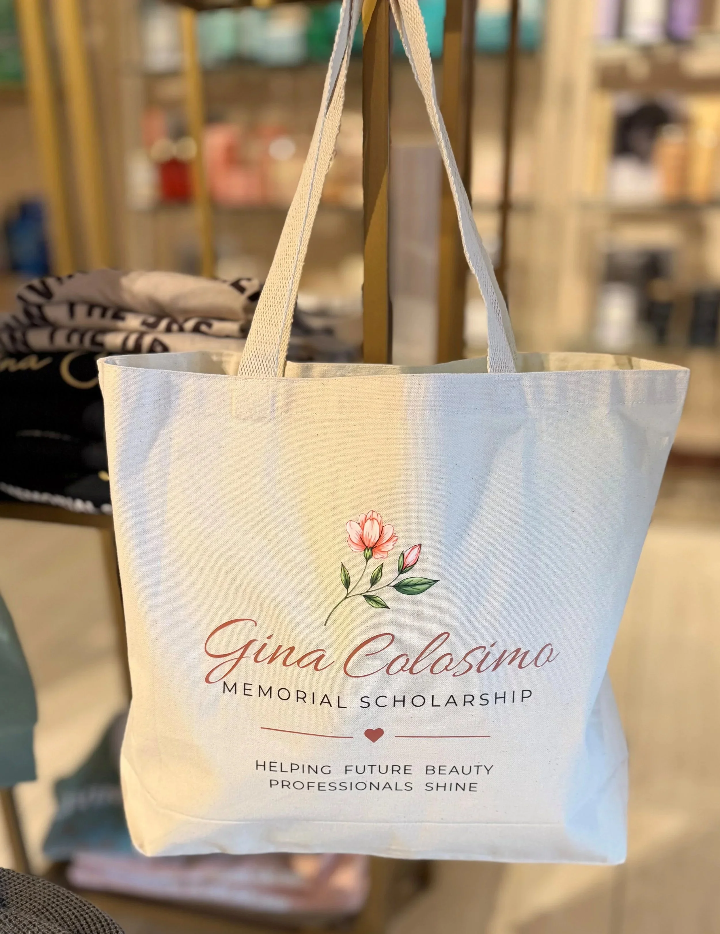 White tote bag with pink flower illustration and text reading 'Gina Colosimo Memorial Scholarship'.