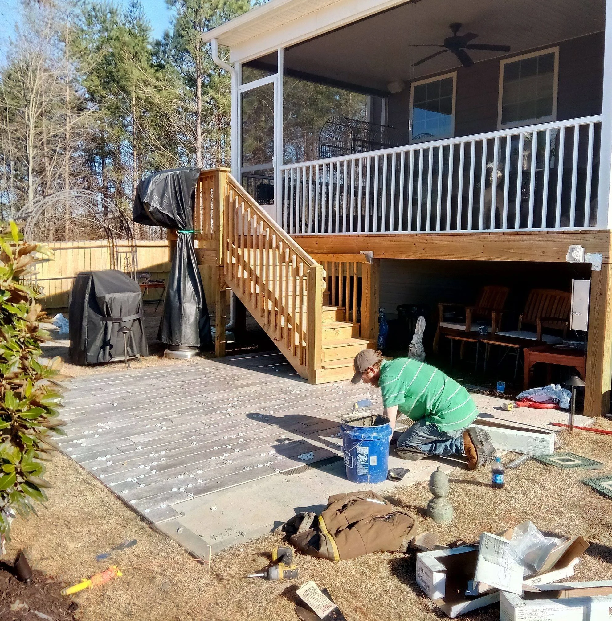 Brighter Solutions Construction Crew Member carefully installing tile under deck stairs. 
