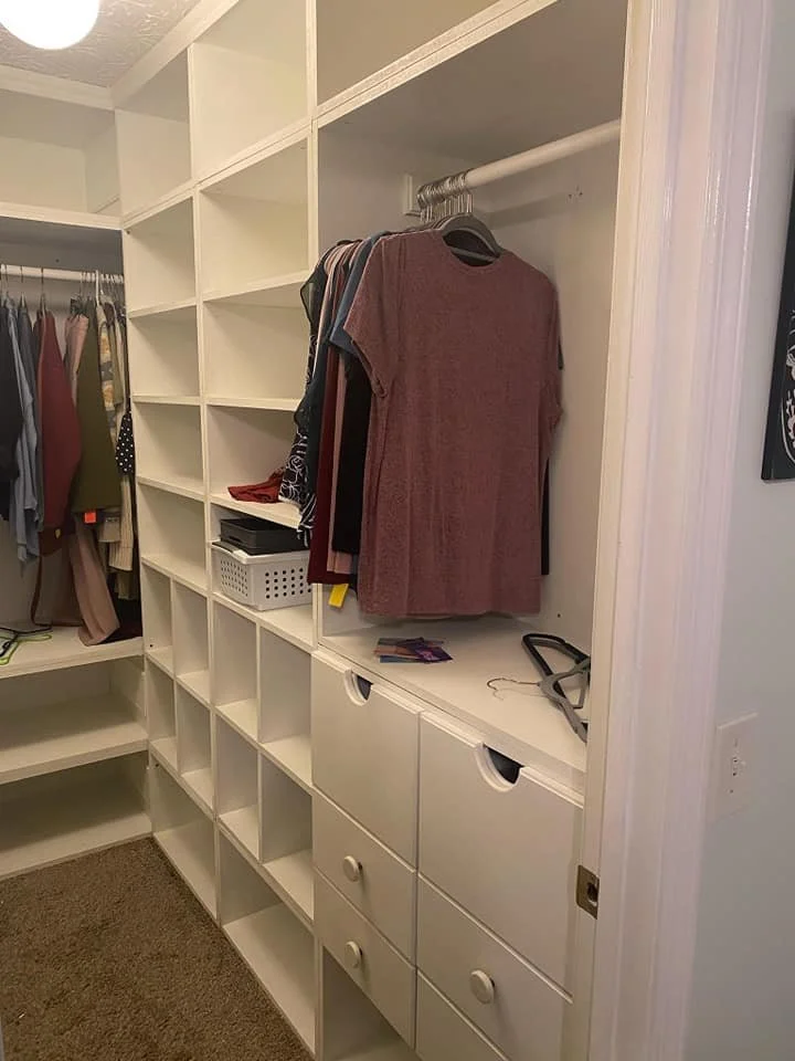 View from doorway of medium sized closet with different sized openings for shoes, accessories and clothes. Closet includes drawers and hanging space. 