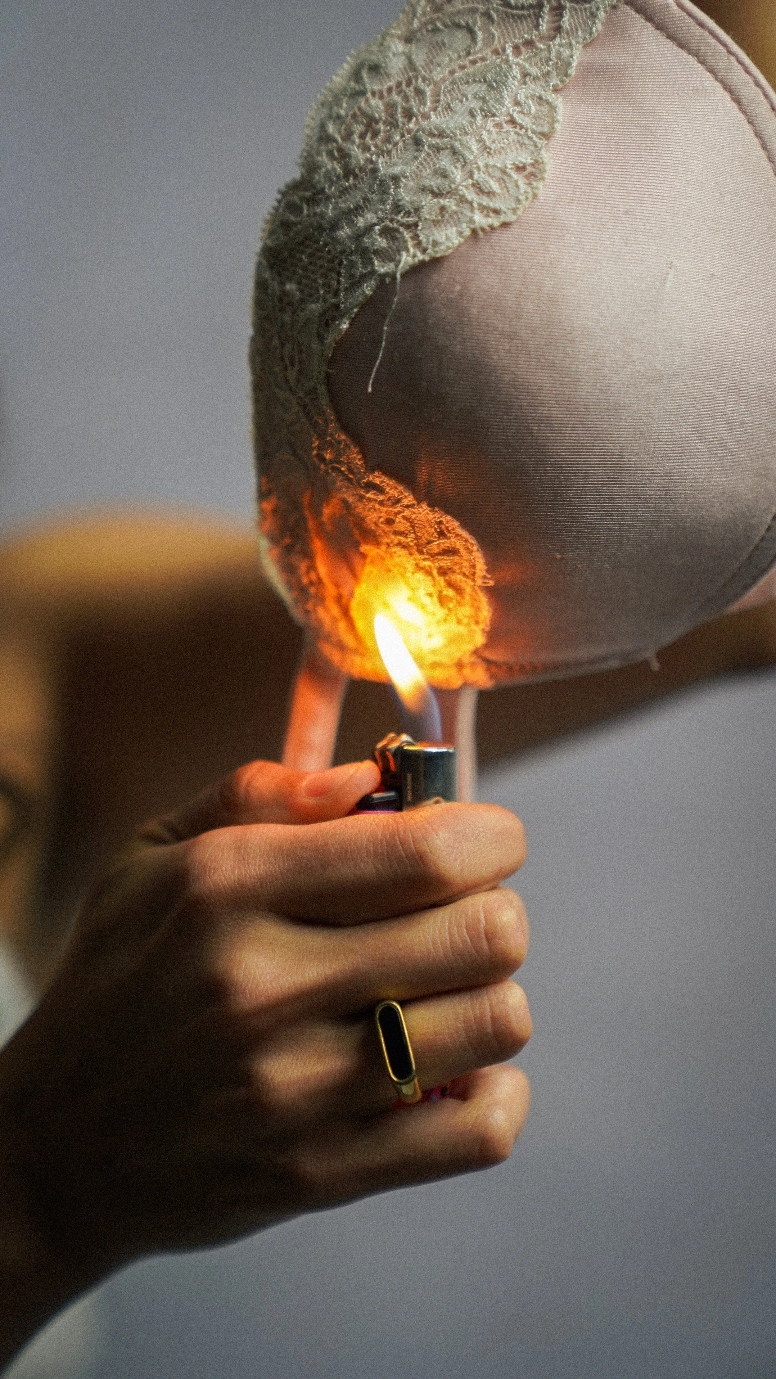 Persona encendiendo una vela con un encendedor, la vela tiene una decoración de tela y encaje, y está siendo preparada para encenderse.