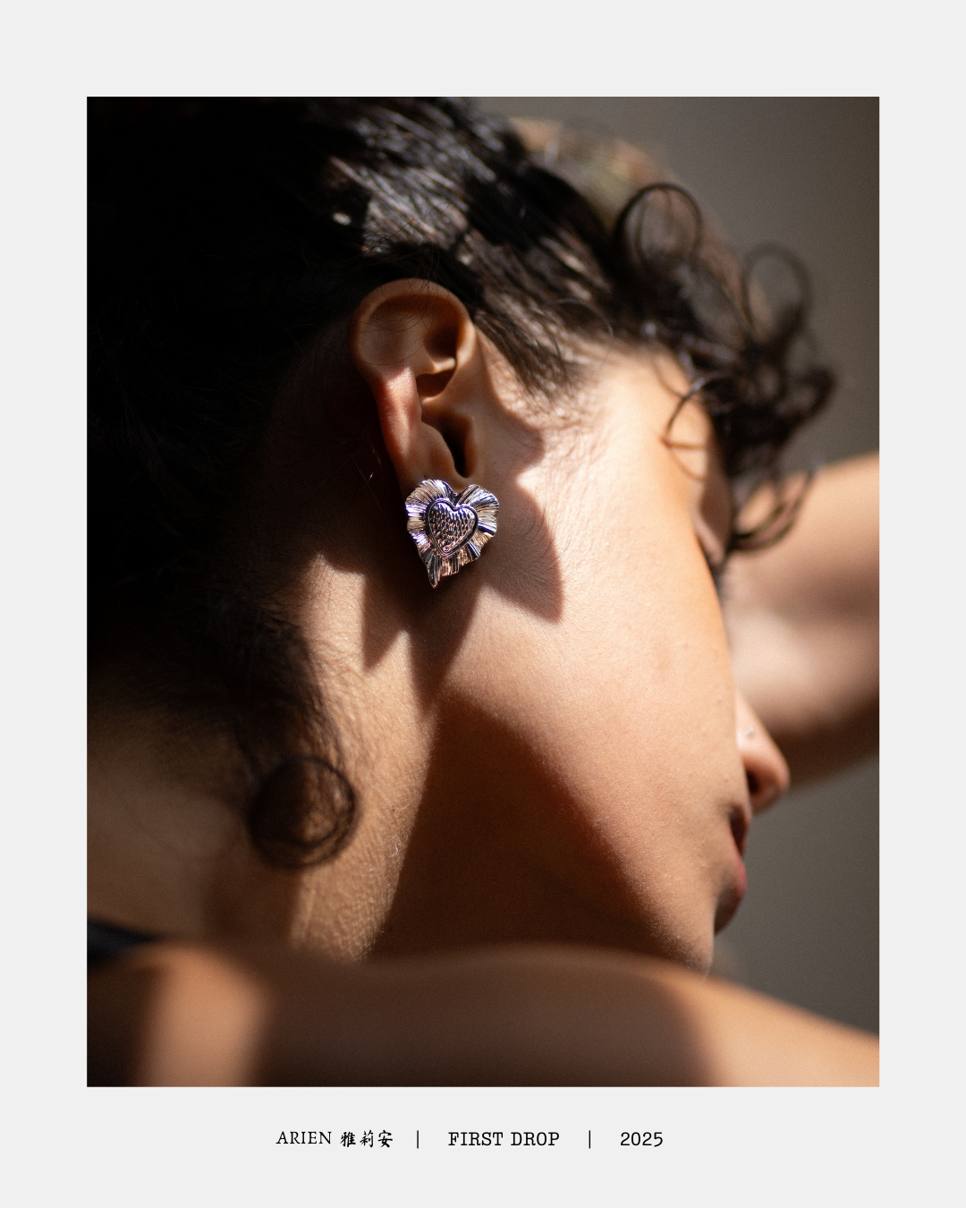 Mujer con pendiente de corazón de plata en la oreja, con sombra en la piel y curvaturas suaves en el rostro y el cuello