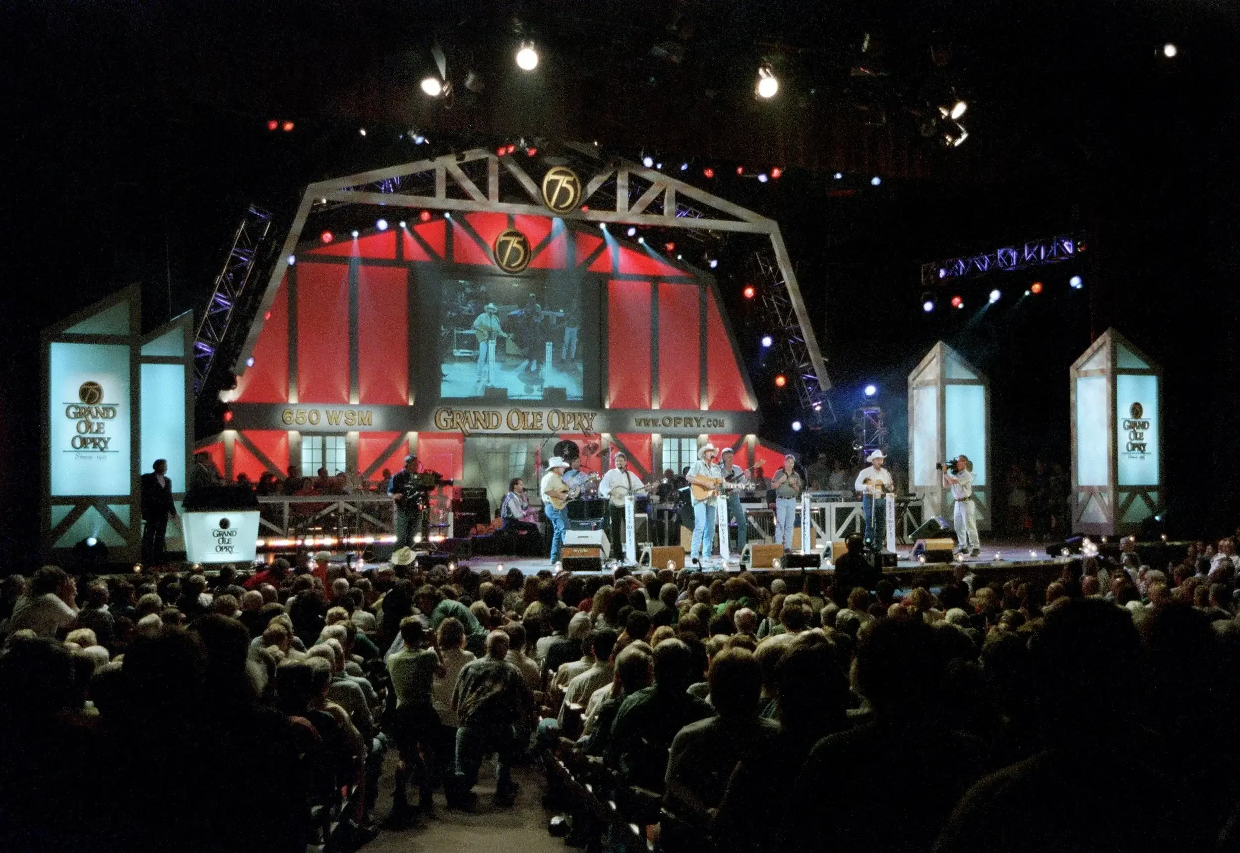 Stage with performers at the Grand Ole Opry, celebrating its 75th anniversary, featuring musicians, audience, and stage lighting.