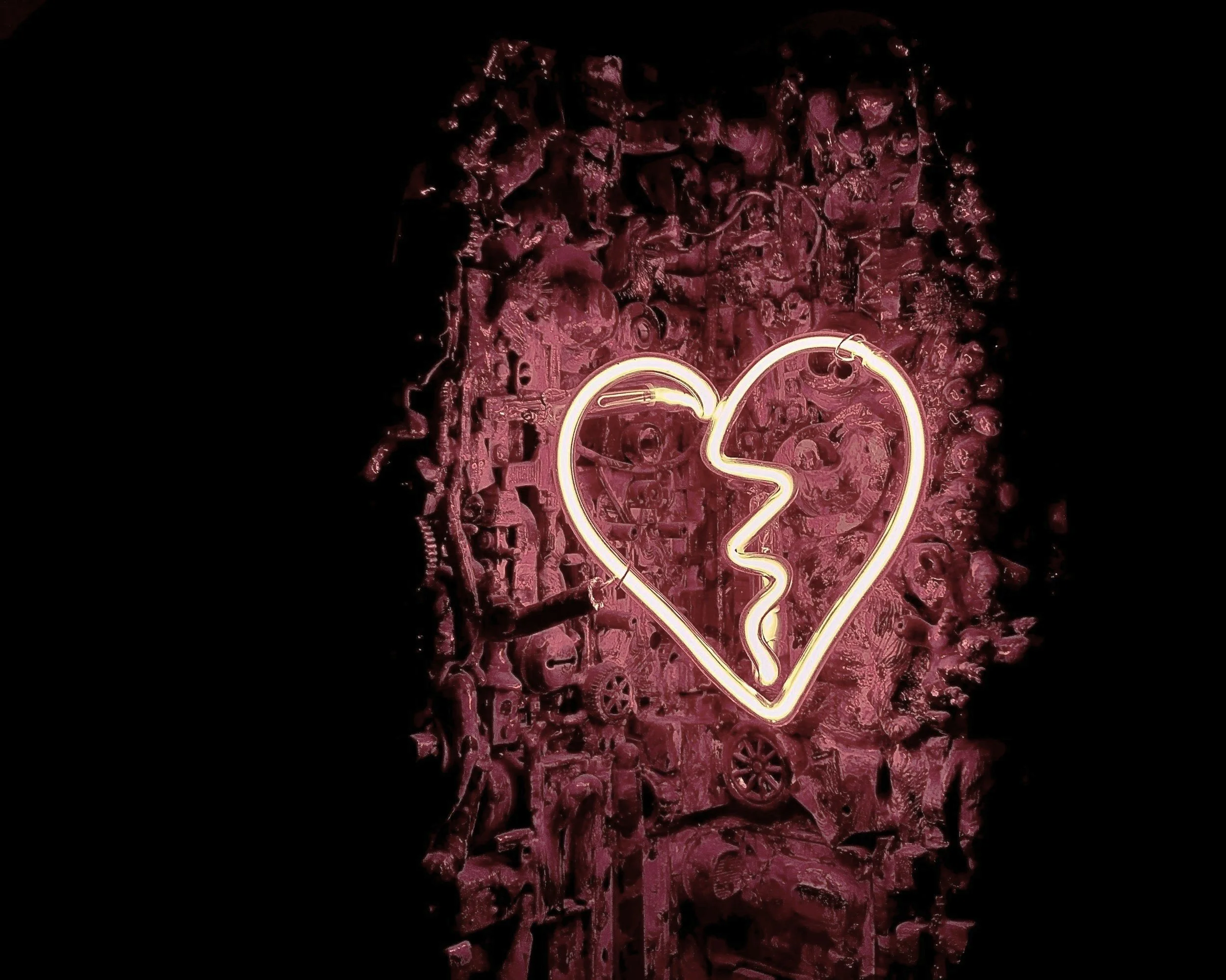 picture of florescent heart in front of broken machines, representing repair of shattered heart