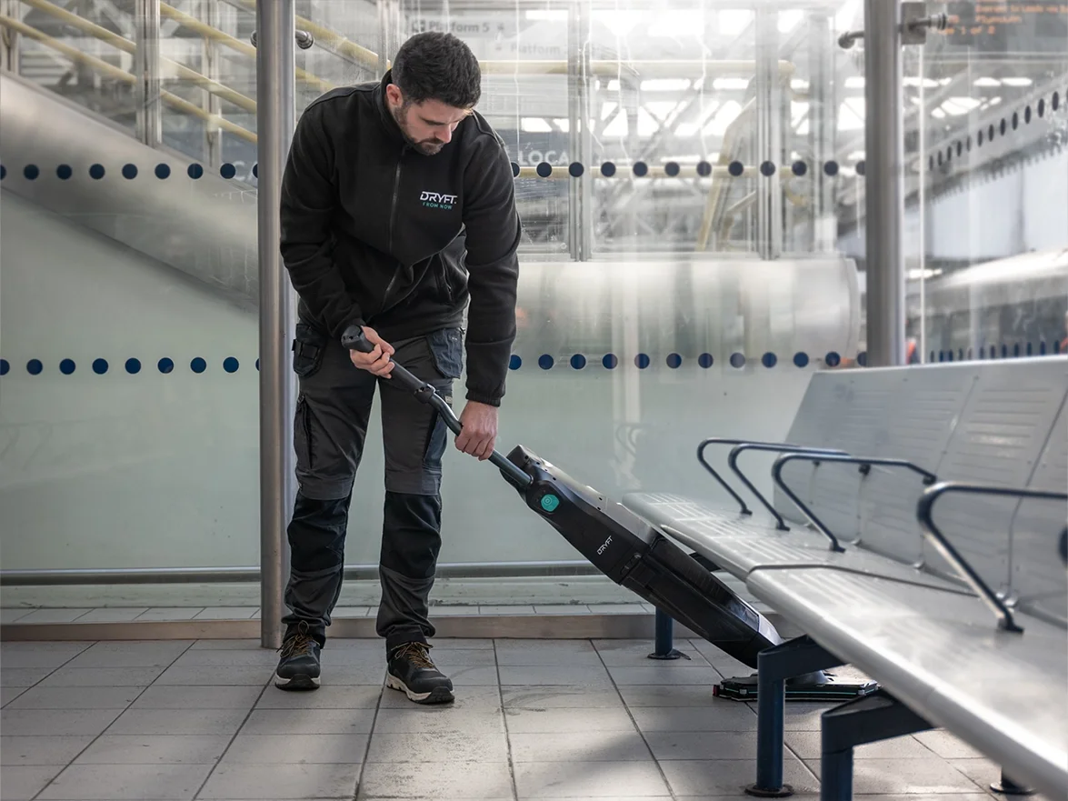 Scrubber Dryer reaching low under seats at train station to clean the floor