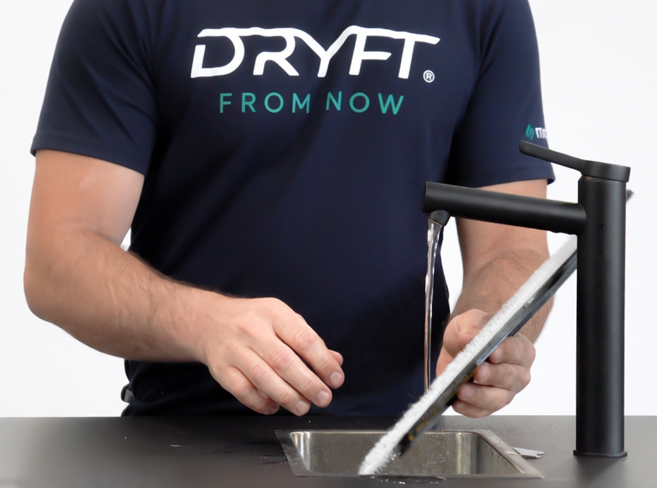 Close-up of a DRYFT cleaning pad being gently peeled away from its black hook-and-loop holder, showing the pad removal process.
