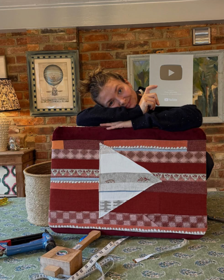 A smiling person: professional upholsterer sitting in her studio.
