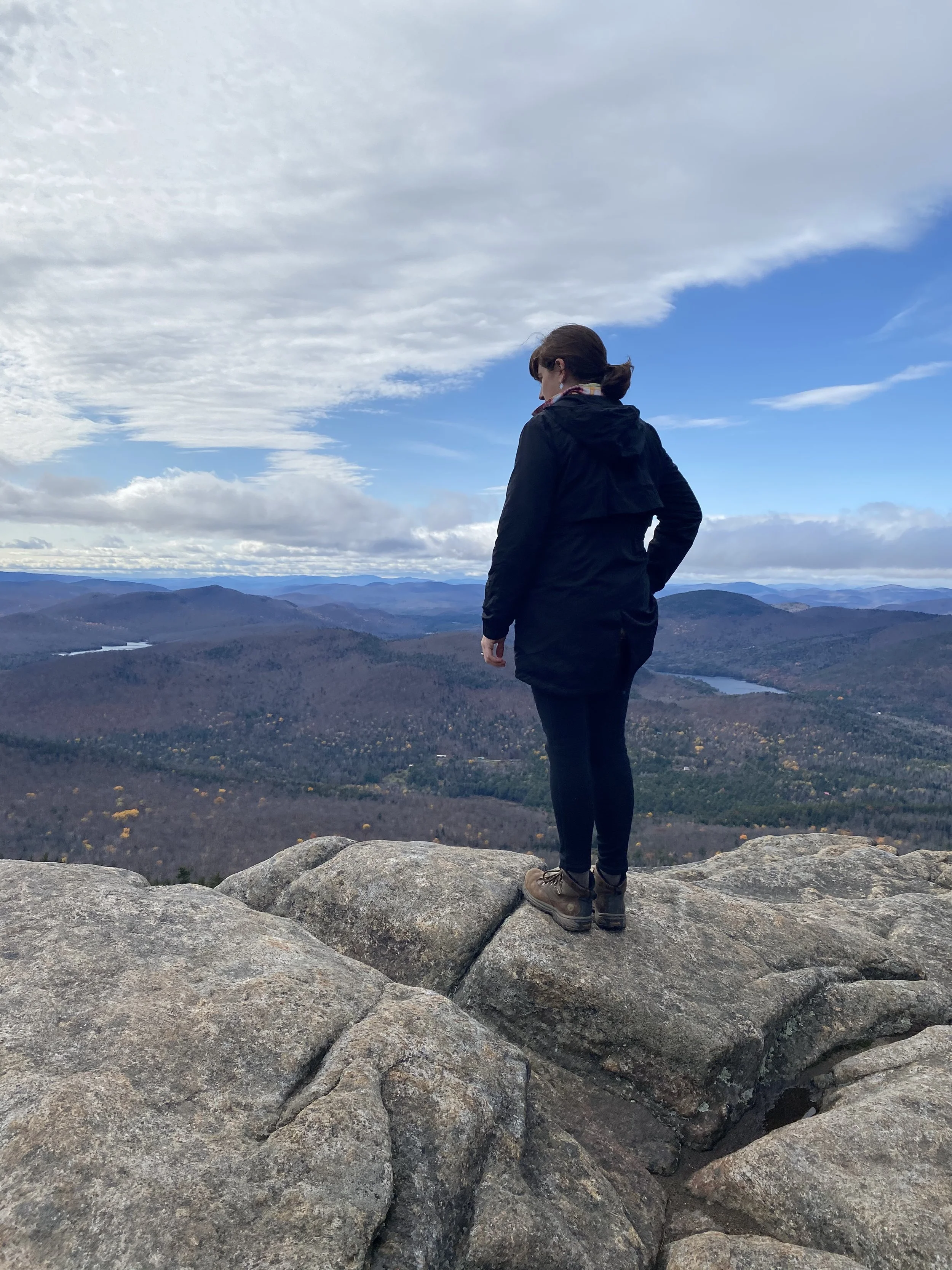 Image of Jessica standing at looking out from the summit of a High Peak in the Adirondacks.