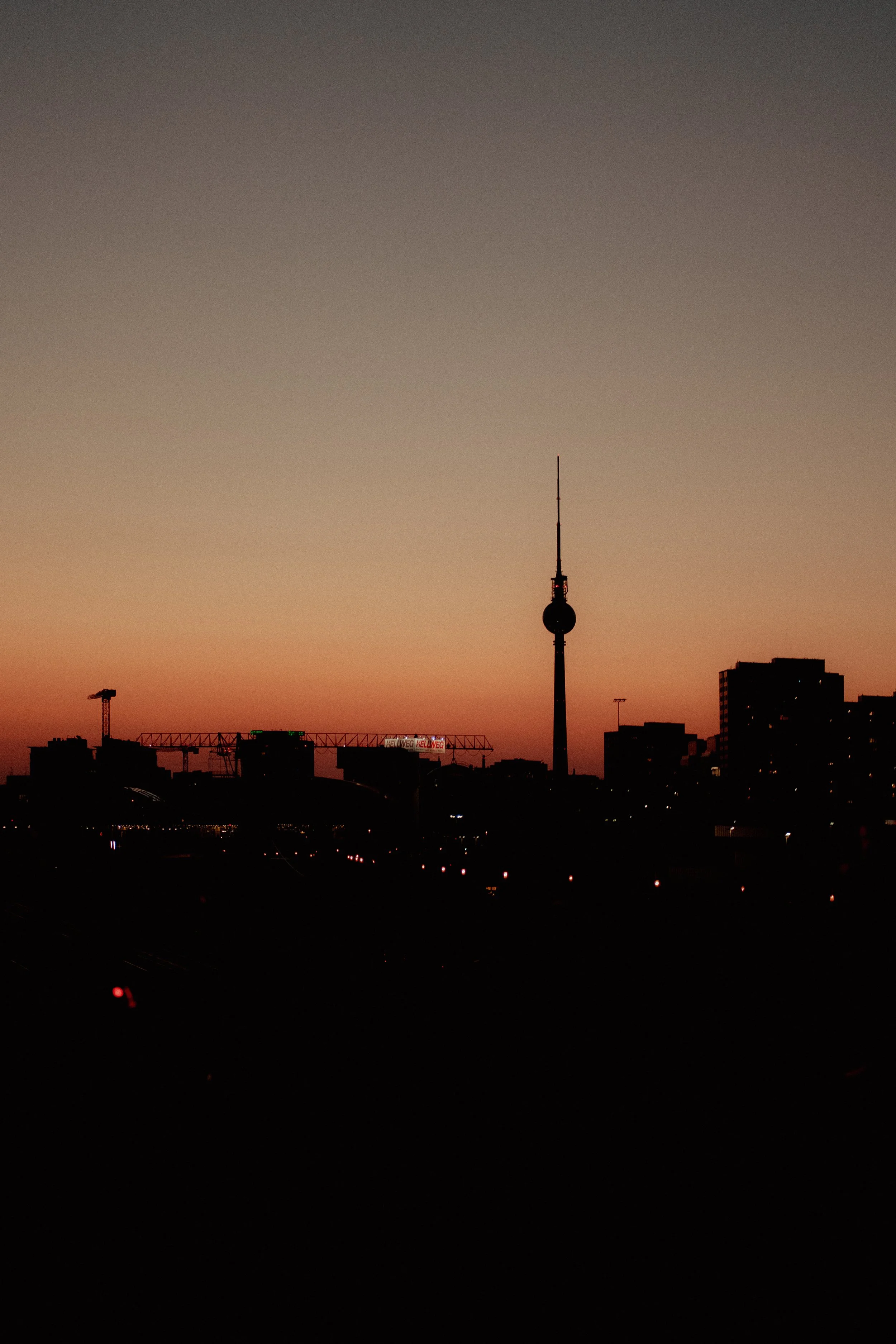 Sonnenuntergang über Berlin mit Skyline, Fernsehturm und Baukränen.