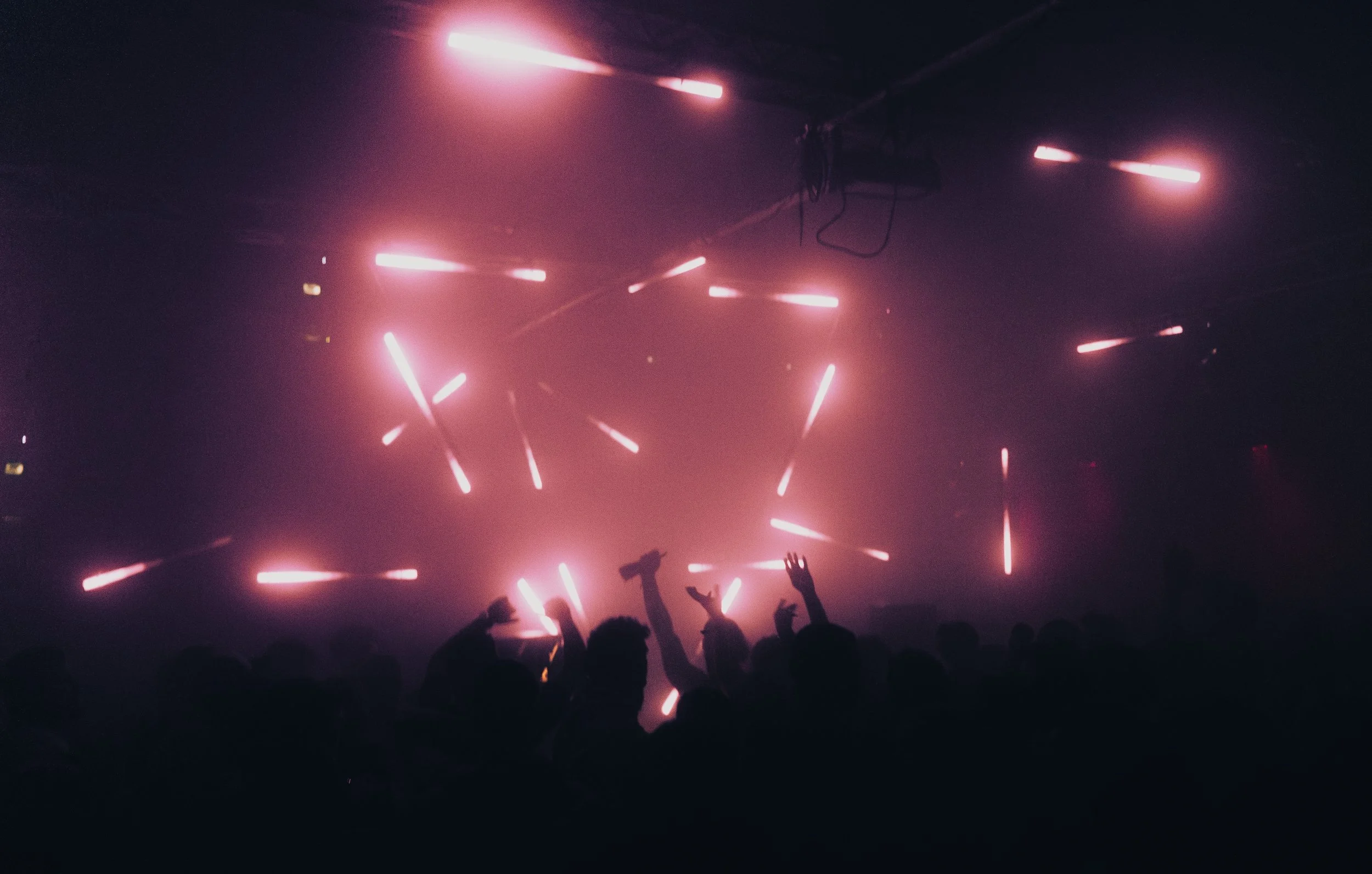 Menschen feiern in einer dunklen Disco mit pinken Lichteffekten.