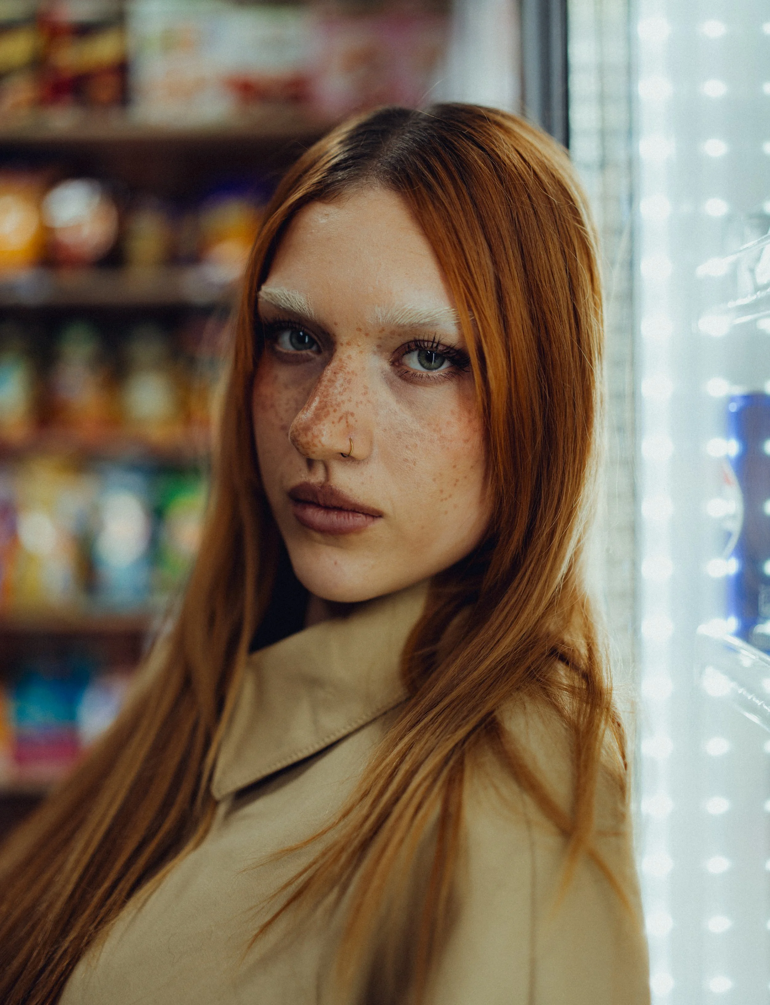 Nahaufnahme eines jungen roten Mädchens mit Sommersprossen in einem Laden, vor einem Getränkeautomaten.