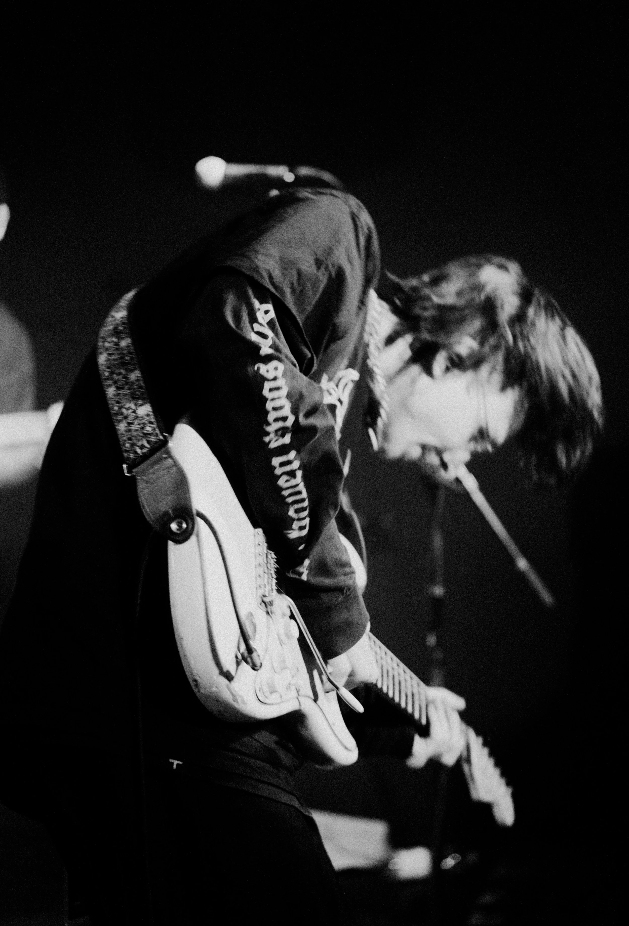 Ein junger Musiker spielt Gitarre und singt bei einer Aufnahme. Es ist eine Schwarz-Weiß-Fotografie, die einen intensiven Moment zeigt.