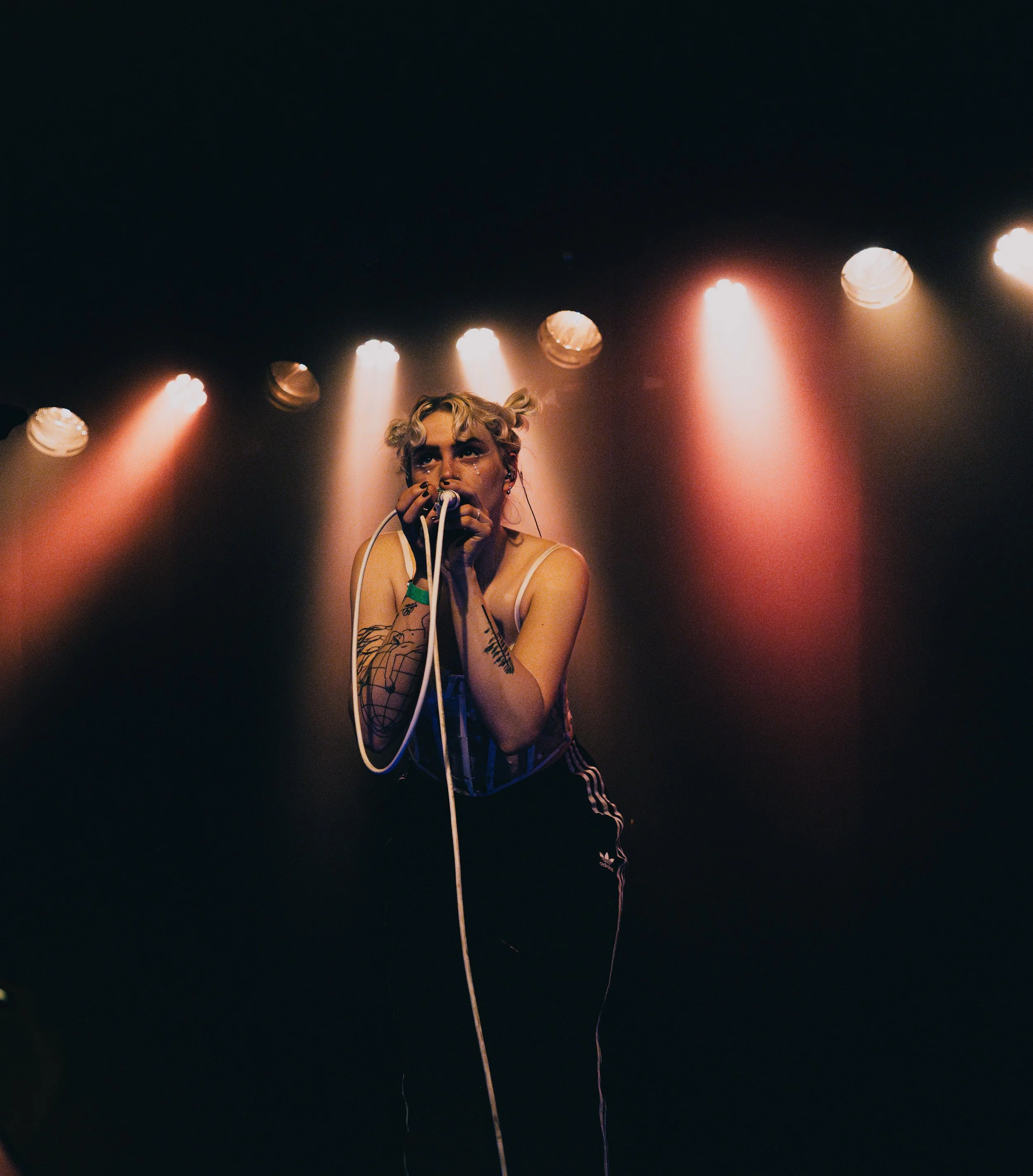 Eine weibliche Sängerin beim Auftritt auf der Bühne, beleuchtet von Scheinwerfern im Hintergrund.