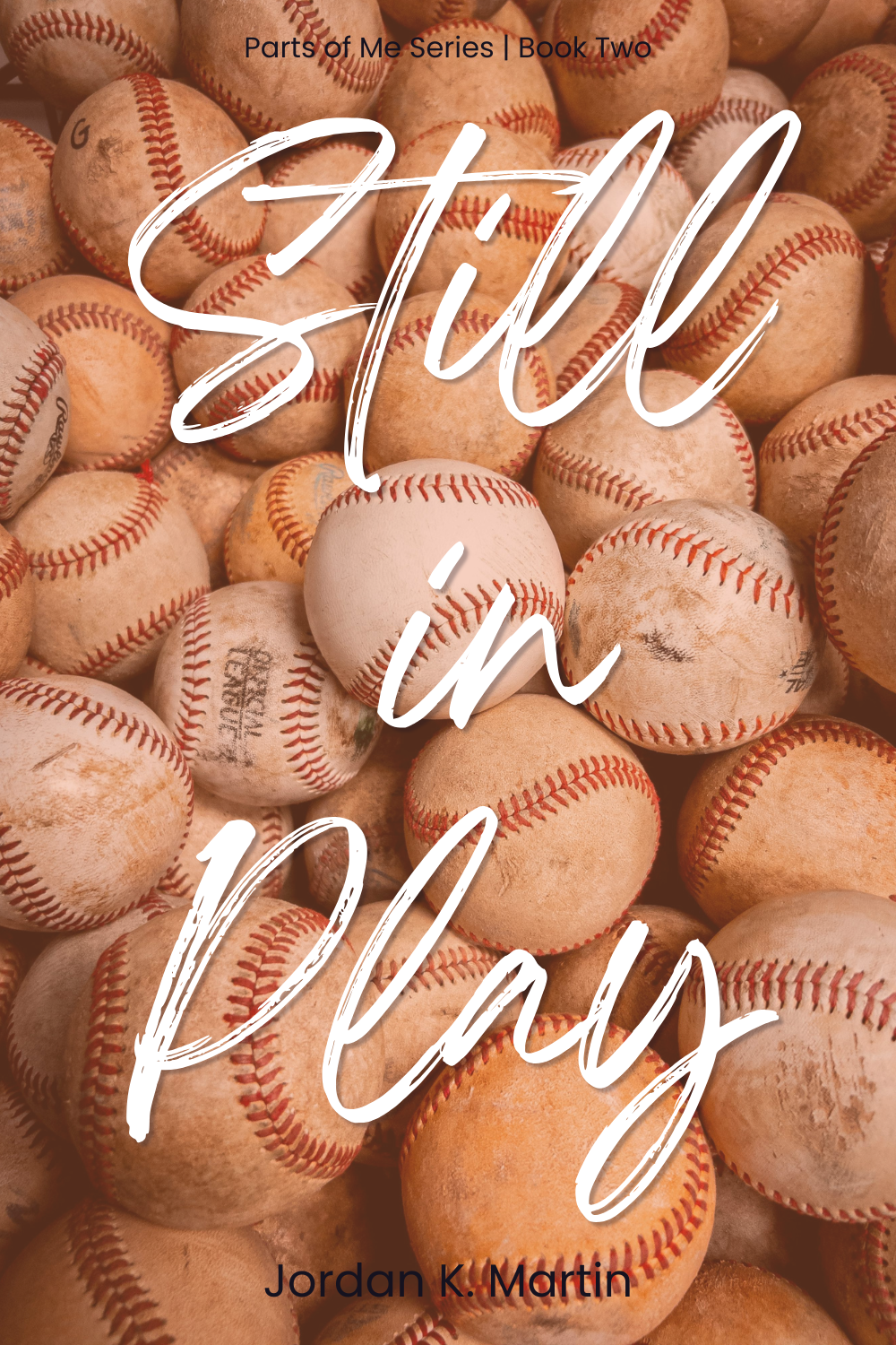 vintage baseballs piled up in the background, with with white handwritten text reading "Still in Play"; Dark Purple Mono font reading "Parts of Me Series Book Two." Text at bottom with authors name in dark purple "Jordan K. Martin"