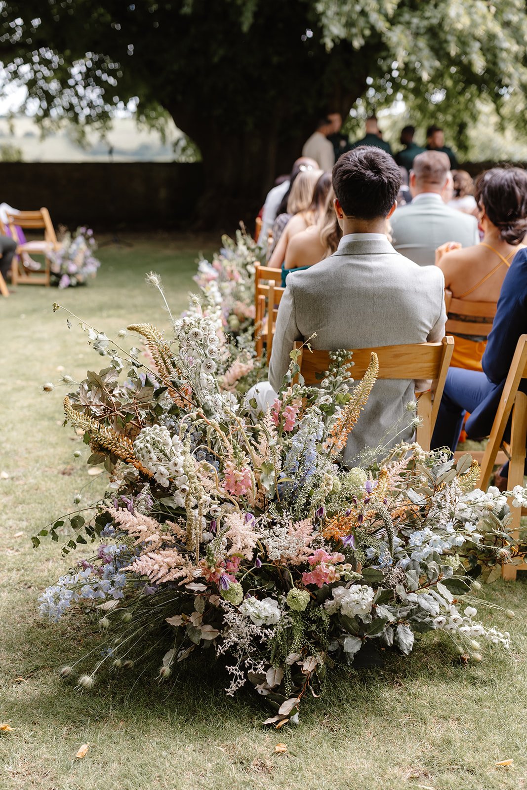 Outdoor ceremony florals at Hamswell House on the edge of the Cotswolds near Bath, with layered meadow planting of astilbe, stocks, delphinium, eremurus, clematis and nigella.