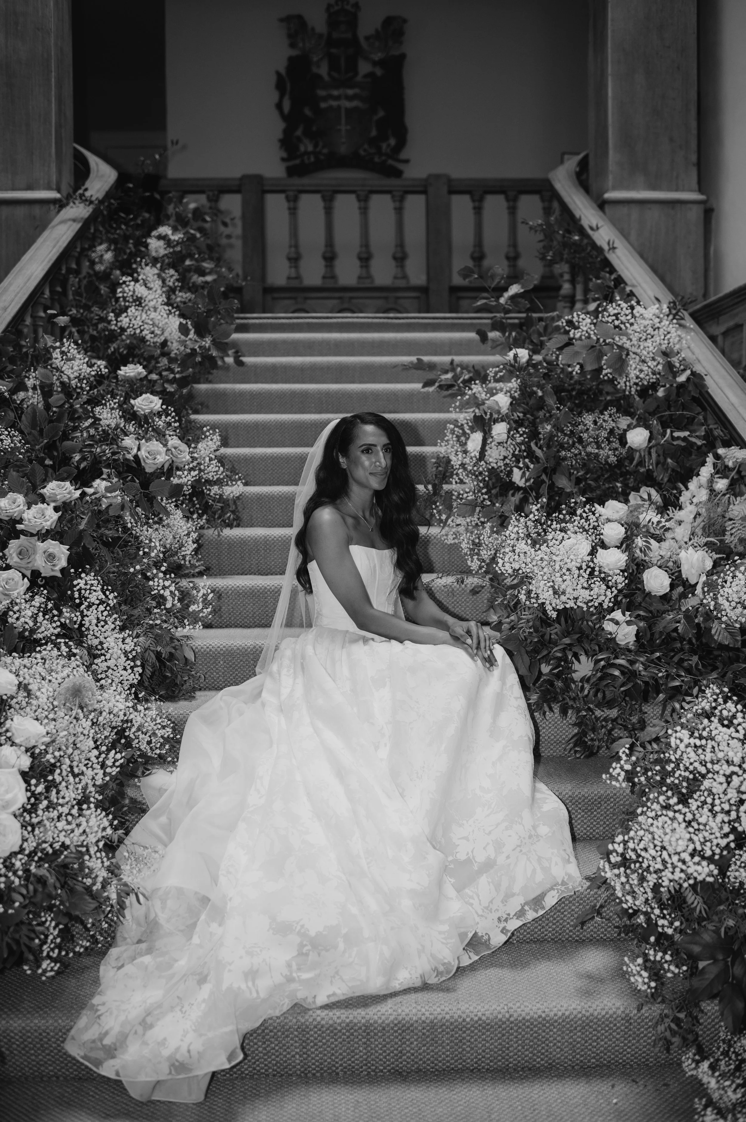 Wedding staircase floral installation at Farleigh House with abundant roses and textural foliage.