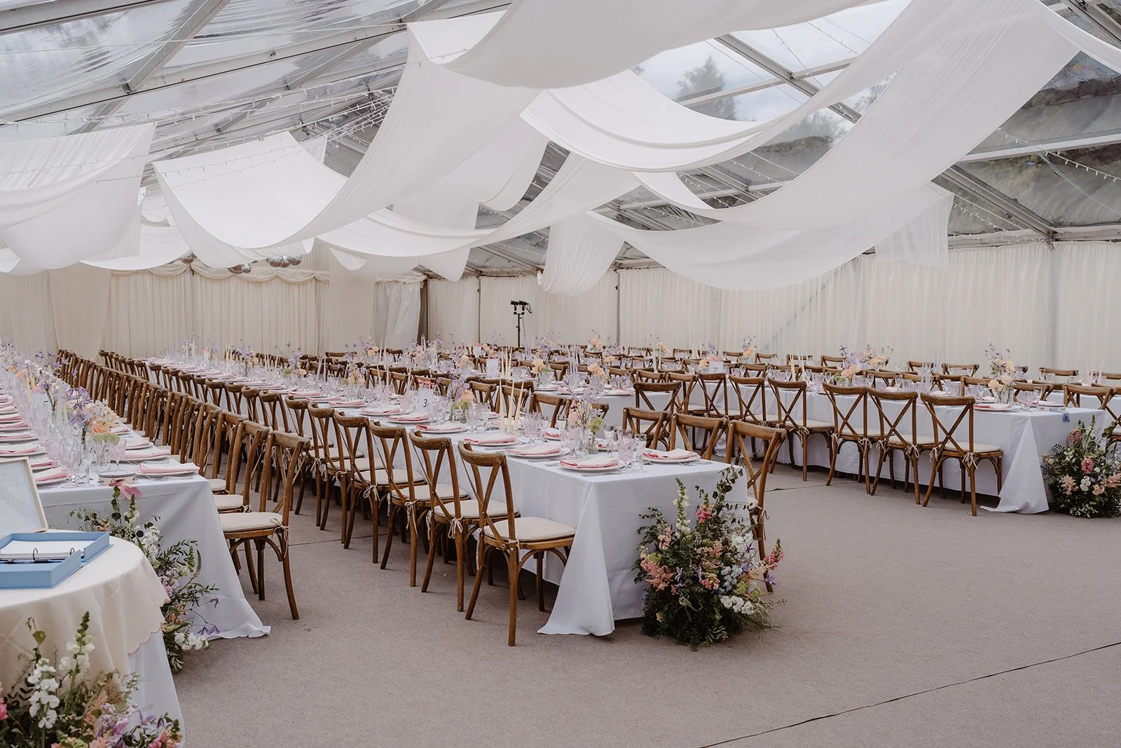 Wedding reception marquee with draped fabric installation and pastel floral arrangements at Hamswell House in Bath