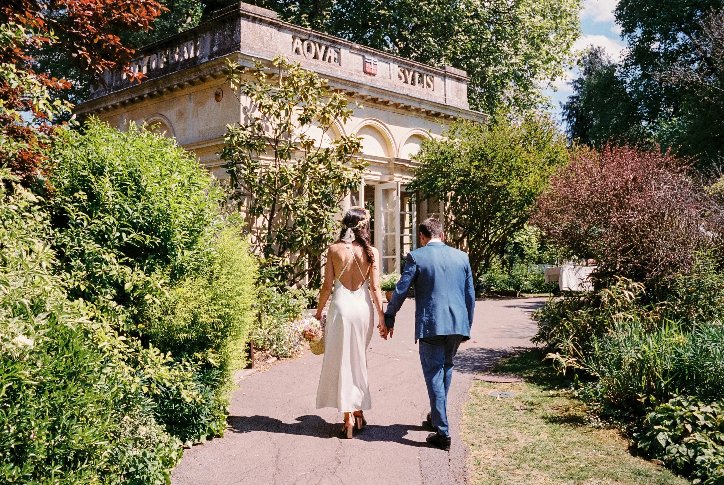 Bride with a basket of spring flowers and a floral crown at the Temple of Minerva, Bath wedding ceremony.