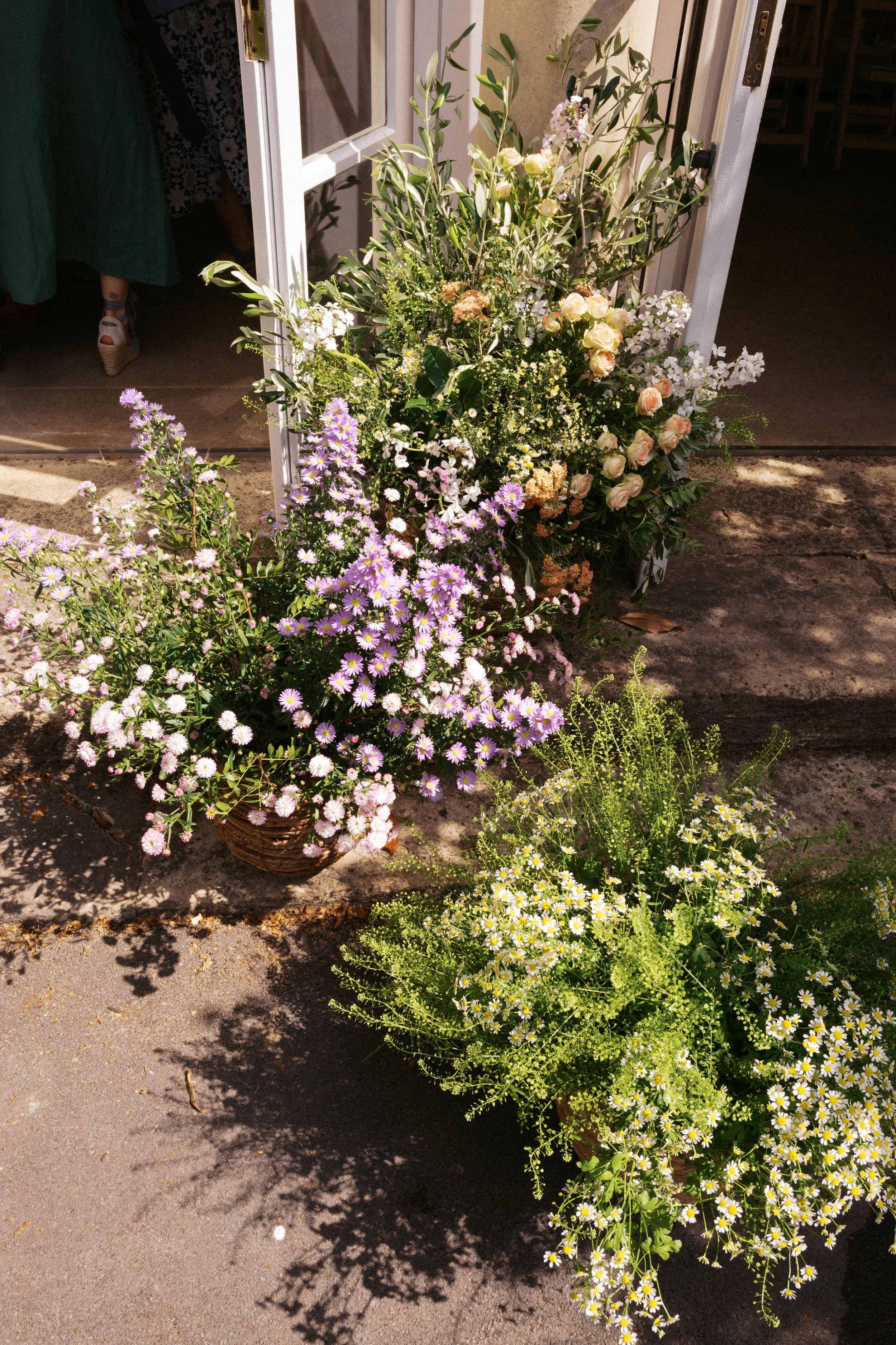 Overflowing baskets of pastel spring wedding flowers at the base of the pillars at the Temple of Minerva, Bath.