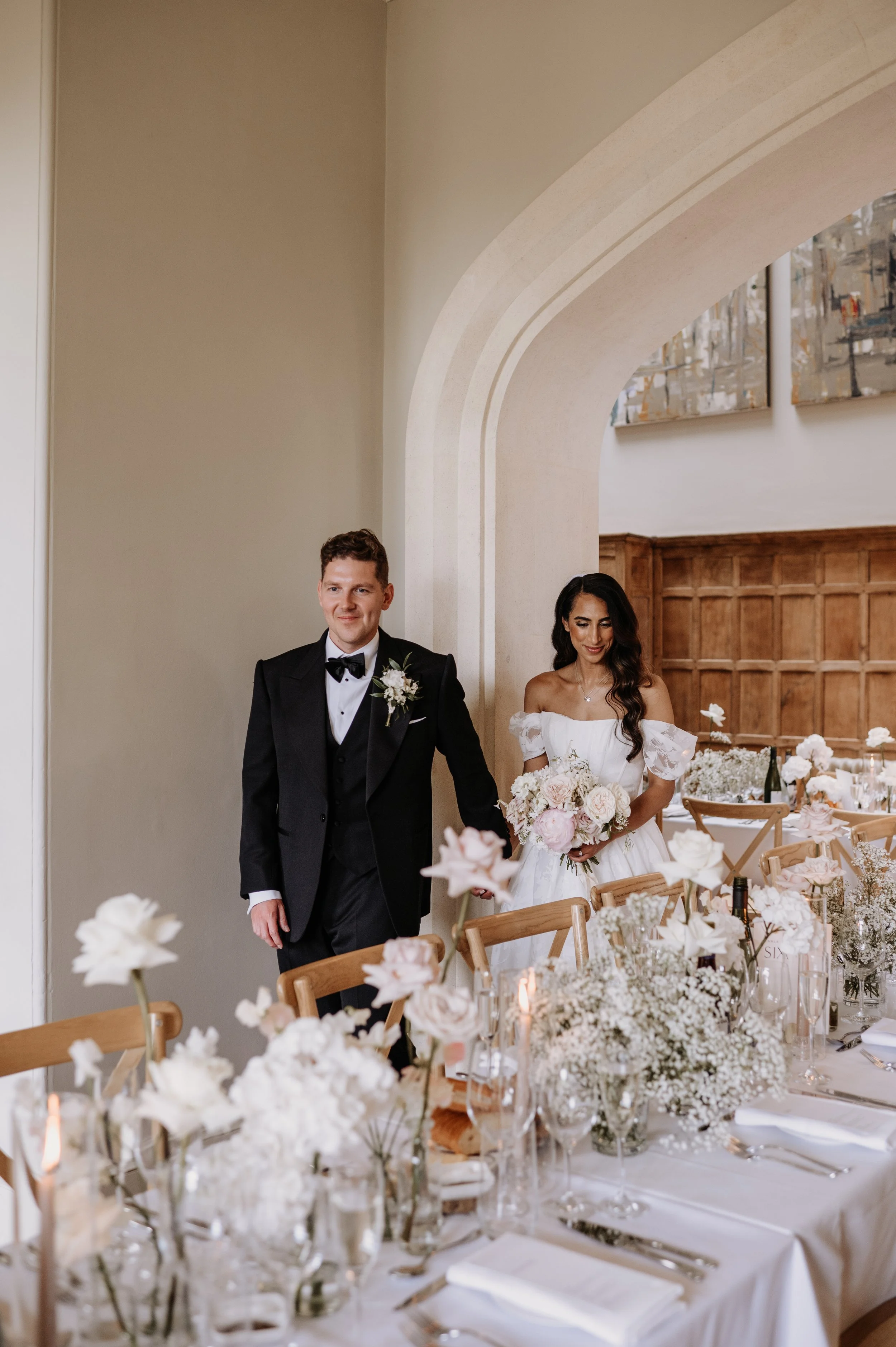 Wedding breakfast table flowers at Farleigh House in Farleigh Hungerford, featuring white and soft blush roses, peonies, hydrangea and gypsophila with candlelight.