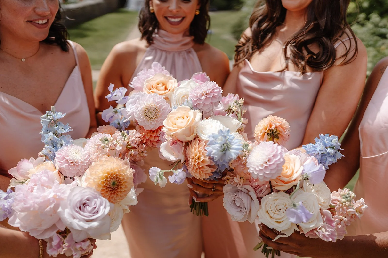 Bridesmaids holding pastel bouquets of dahlias, delphinium, sweet peas and peonies at an Indian wedding at Hamswell House in Bath