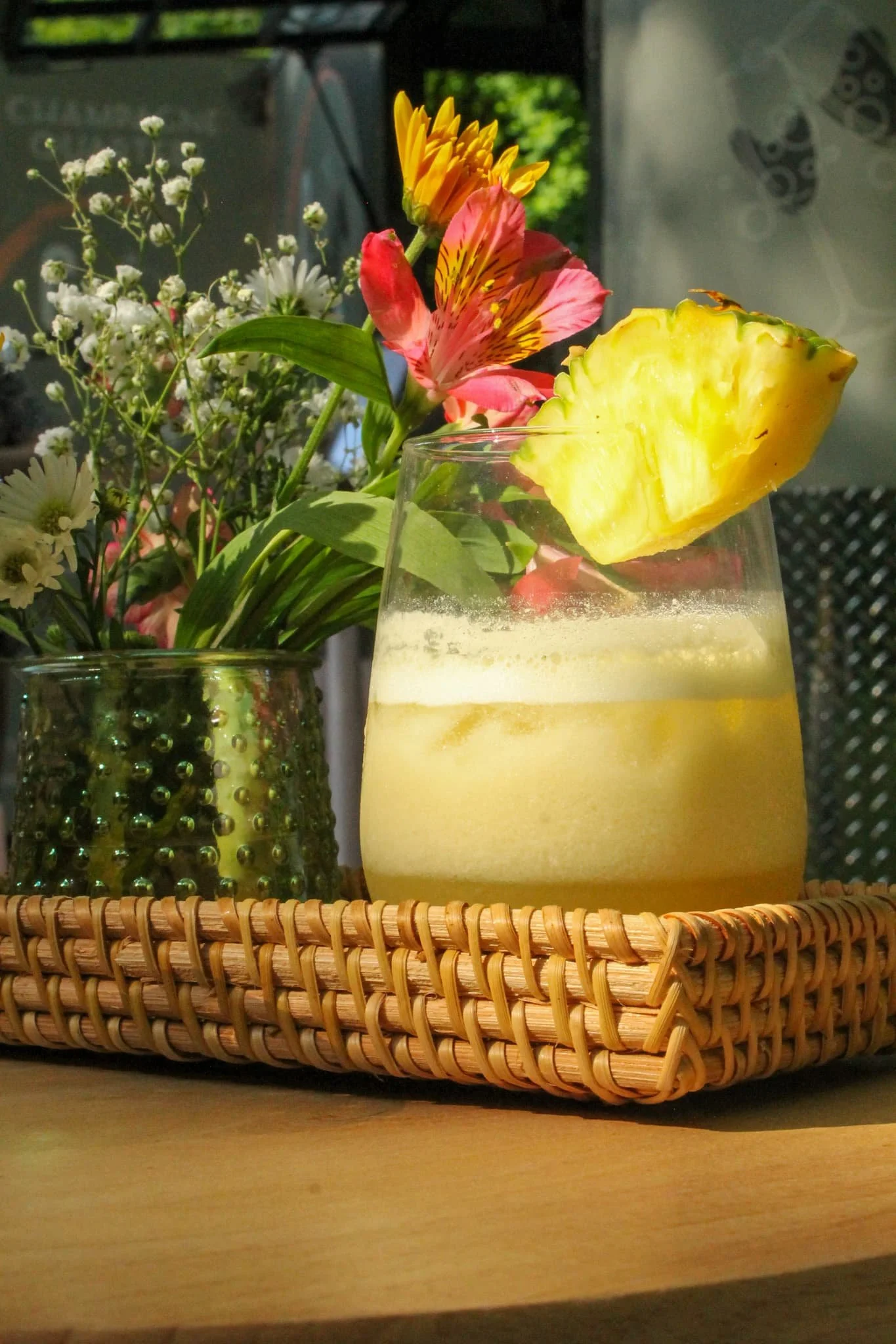 Champagne Quarters mobile bar offering yellow cocktail with fun colored flowers.