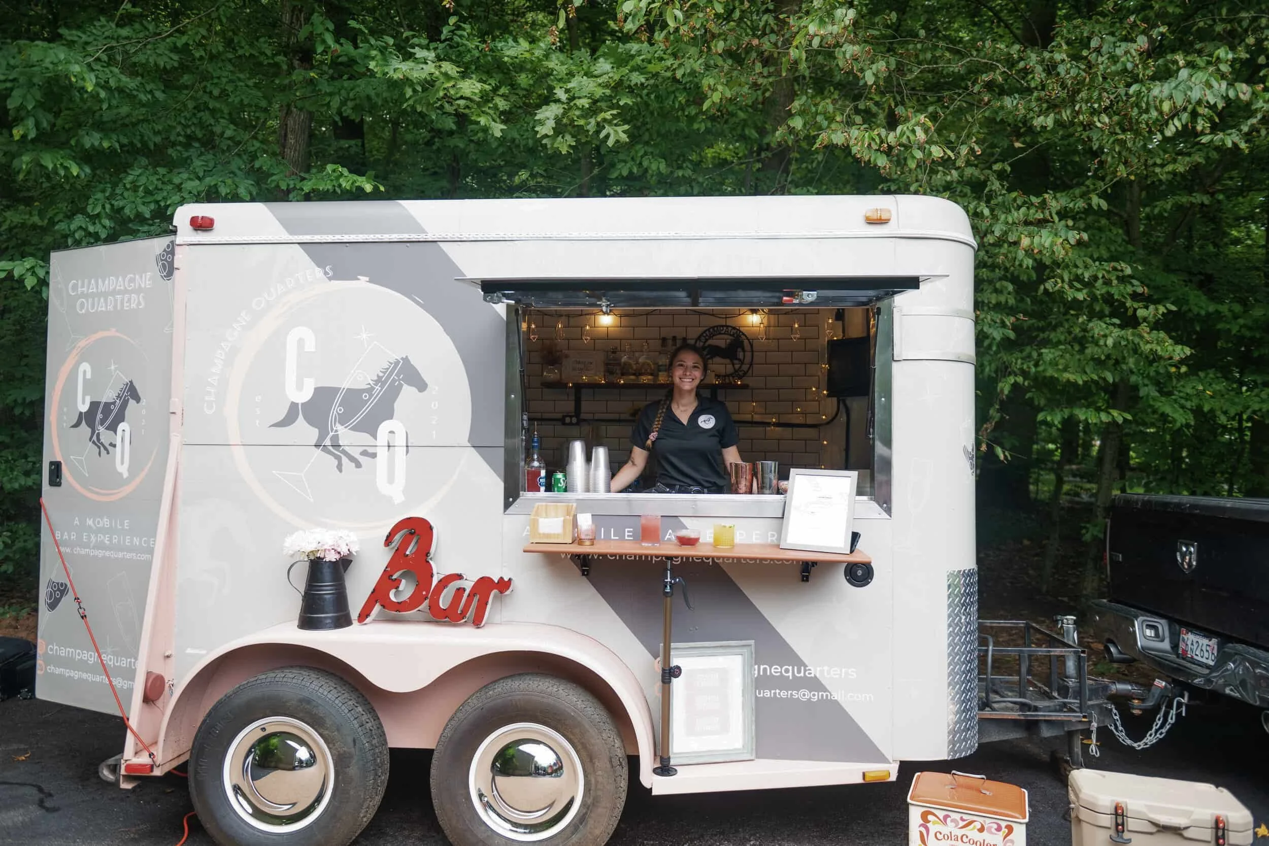 Champagne Quarters horse trailer mobile bar and a female bartender inside the trailer serving cocktails at private event in Maryland.