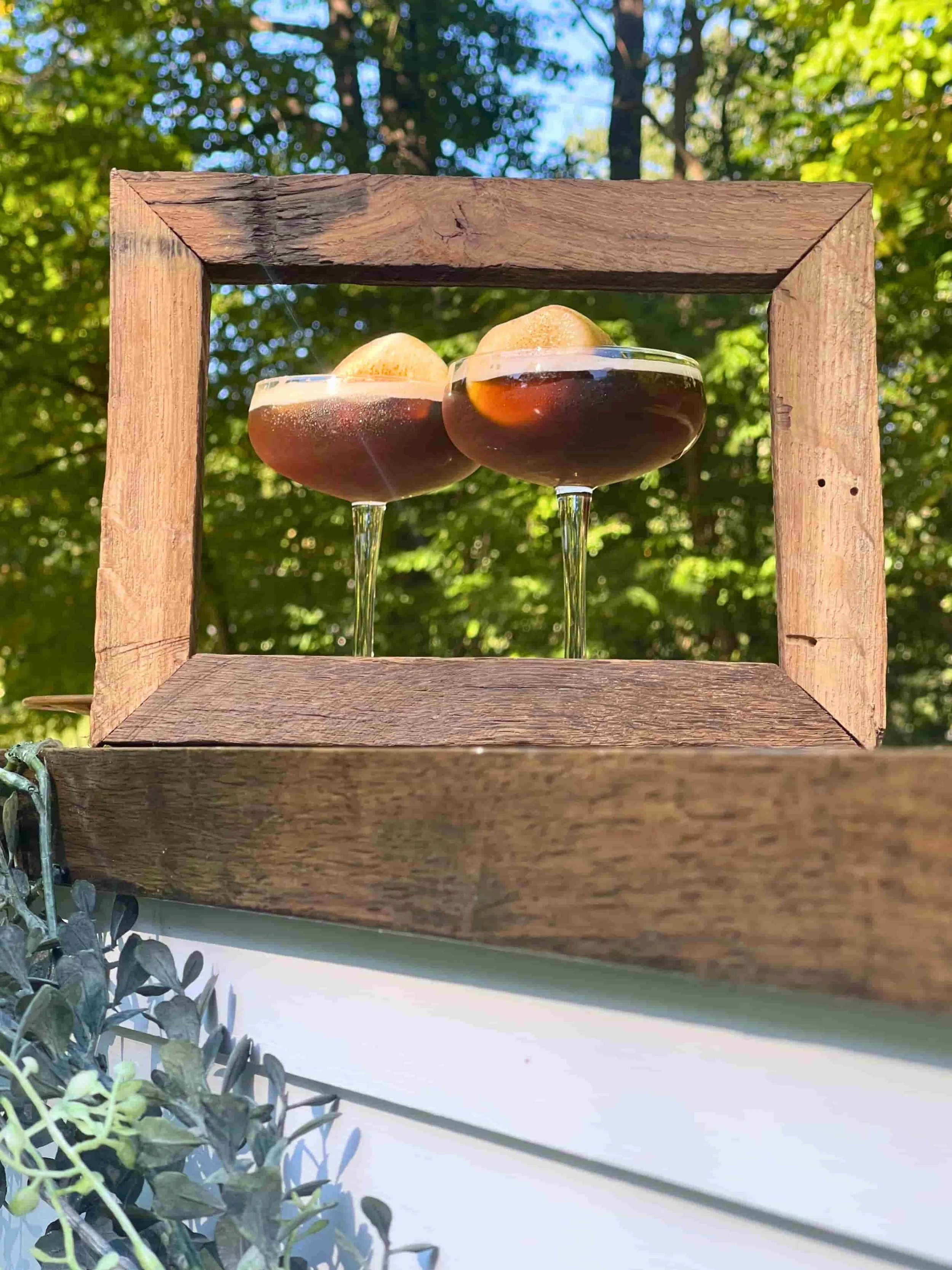 Champagne Quarters mobile bar showing 2 espresso martinis within a wooden frame, on a wooden bar top.
