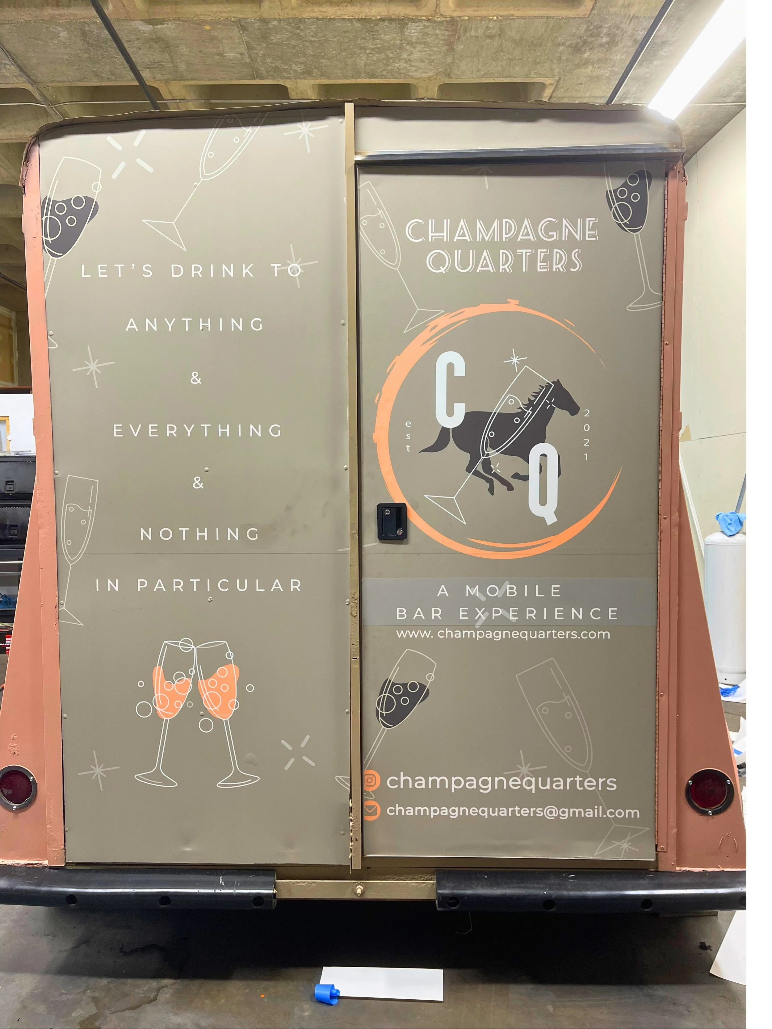 A mobile bar truck with branding for Champagne Quarters, featuring a logo with a horse and champagne glasses, and tagline "Let's drink to anything & everything & nothing in particular."