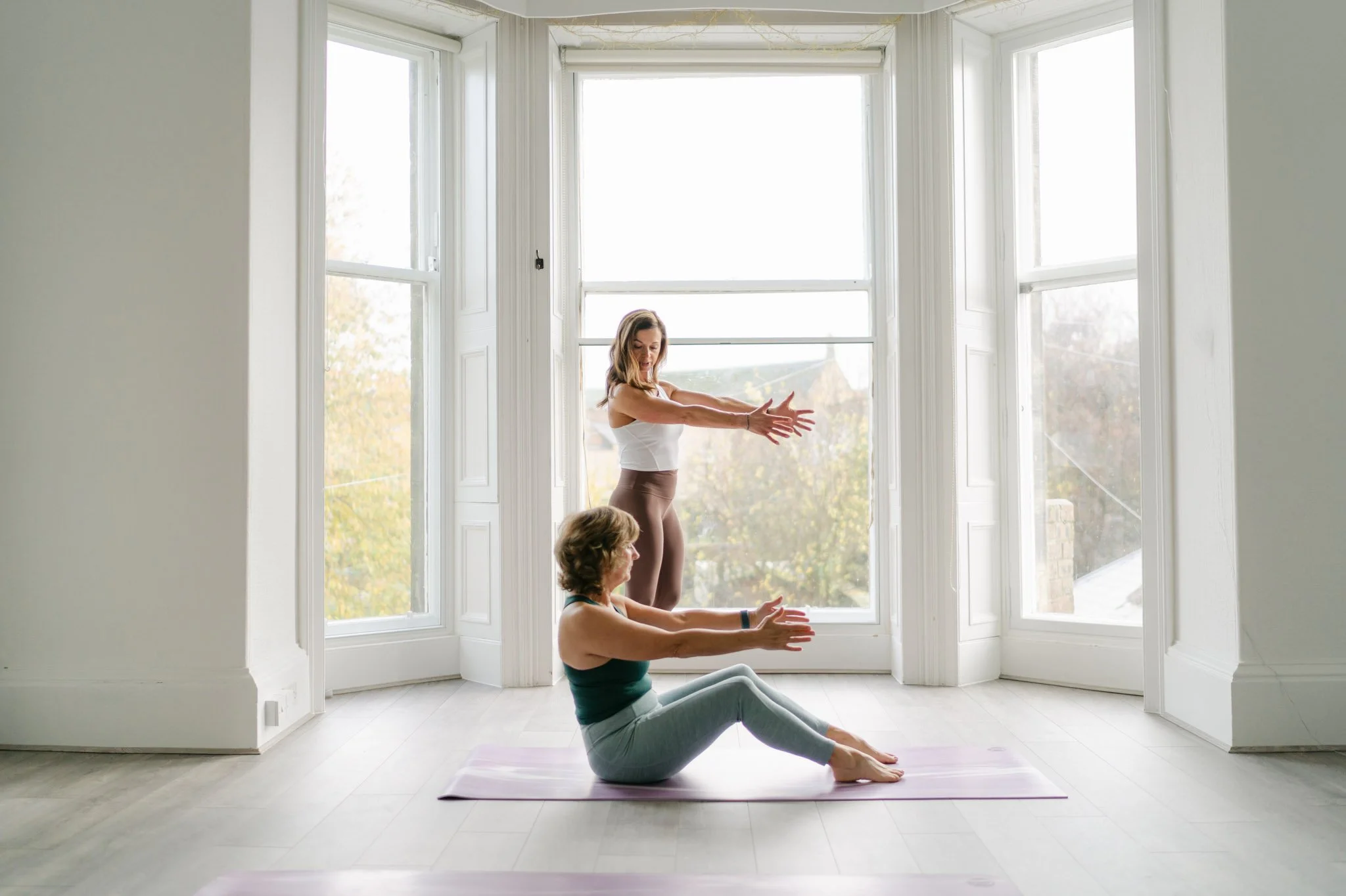Pilates teacher photographed while showing her client the correct pose