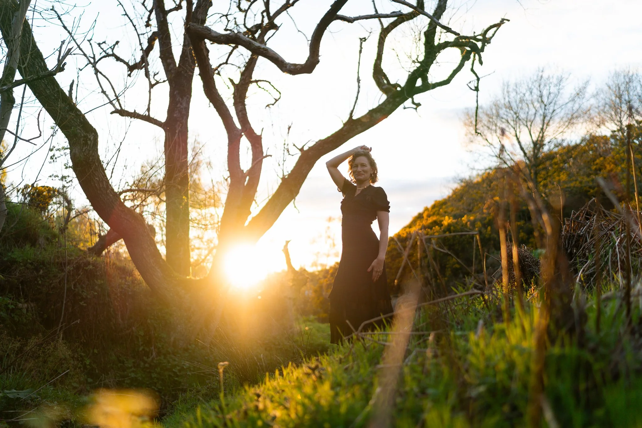 Female astrocartographer photographed wearing black dress and standing against setting sun