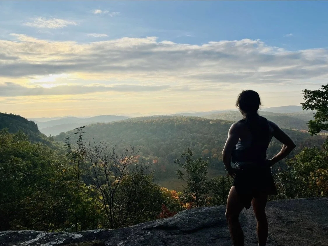 Woman standing in Gatineau Park overlooking fall colours.