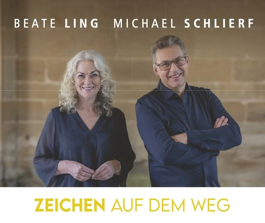 Ein Mann und eine Frau stehen vor einer Wand und lächeln in die Kamera