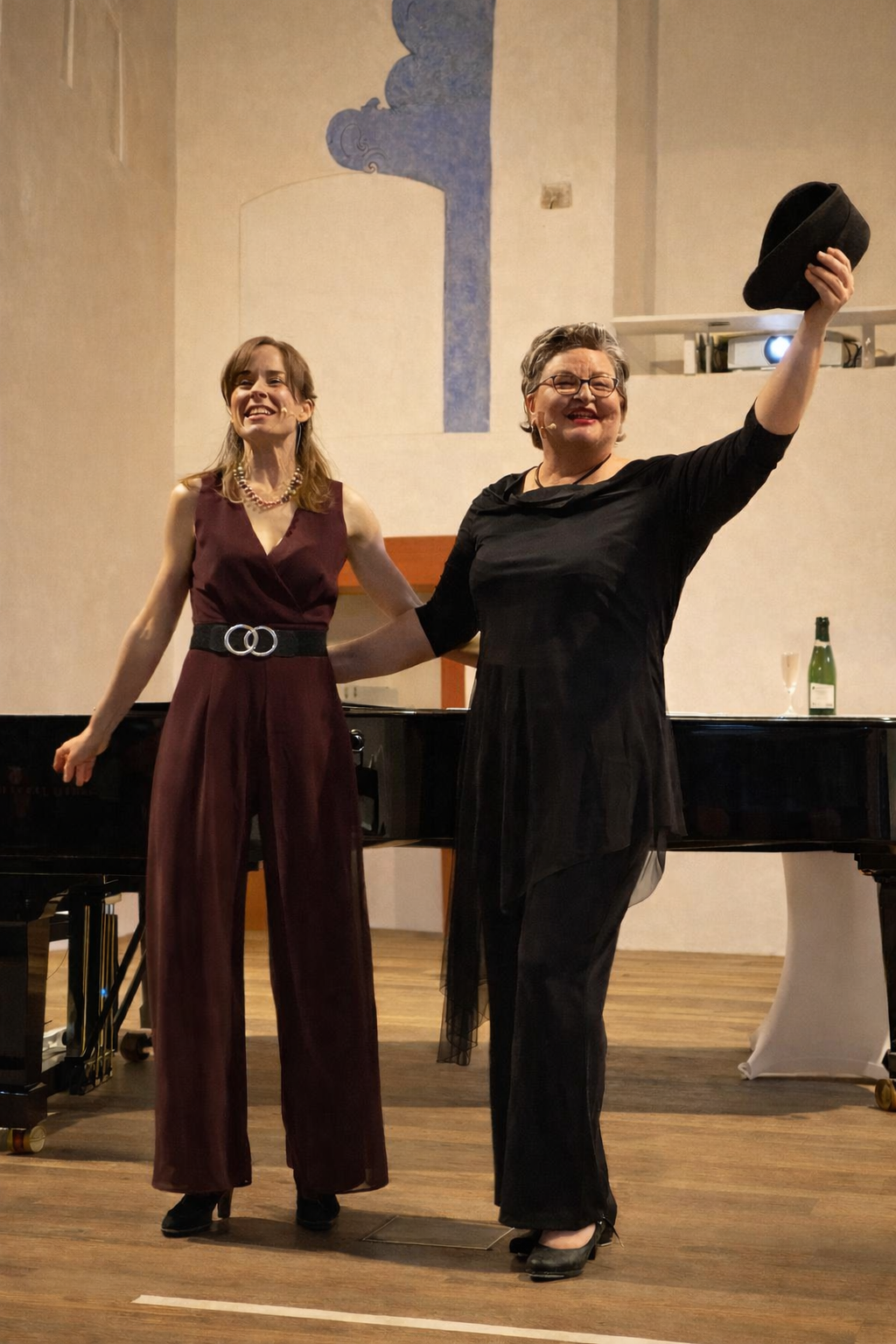 Zwei Frauen stehen vor einem Klavier und schauen ins Publikum