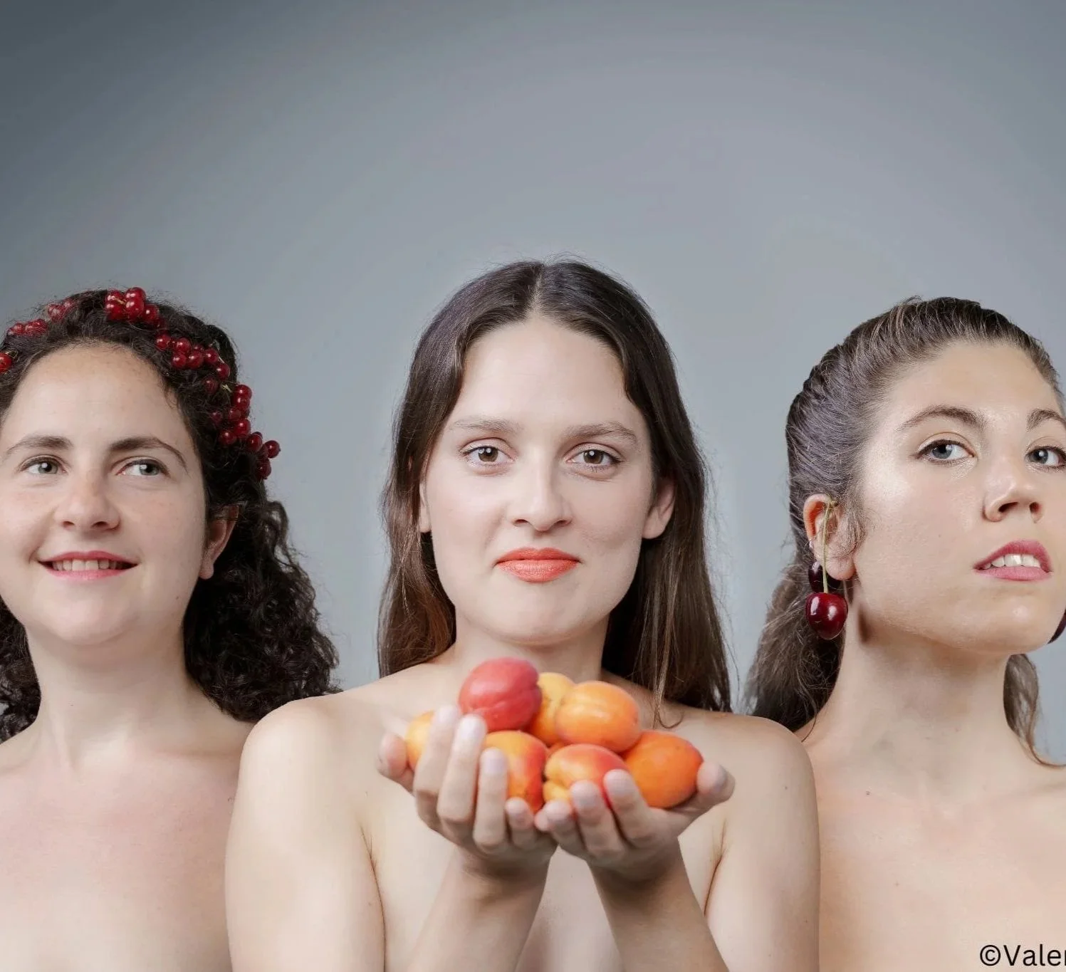 Drei Frauen schauen in die Kamera, die mittlere hält Aprikosen in den Händen.