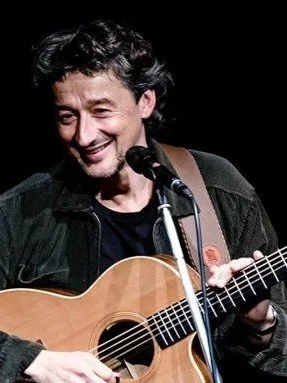 Ein Mann mit Gitarre steht am Mikrofon
