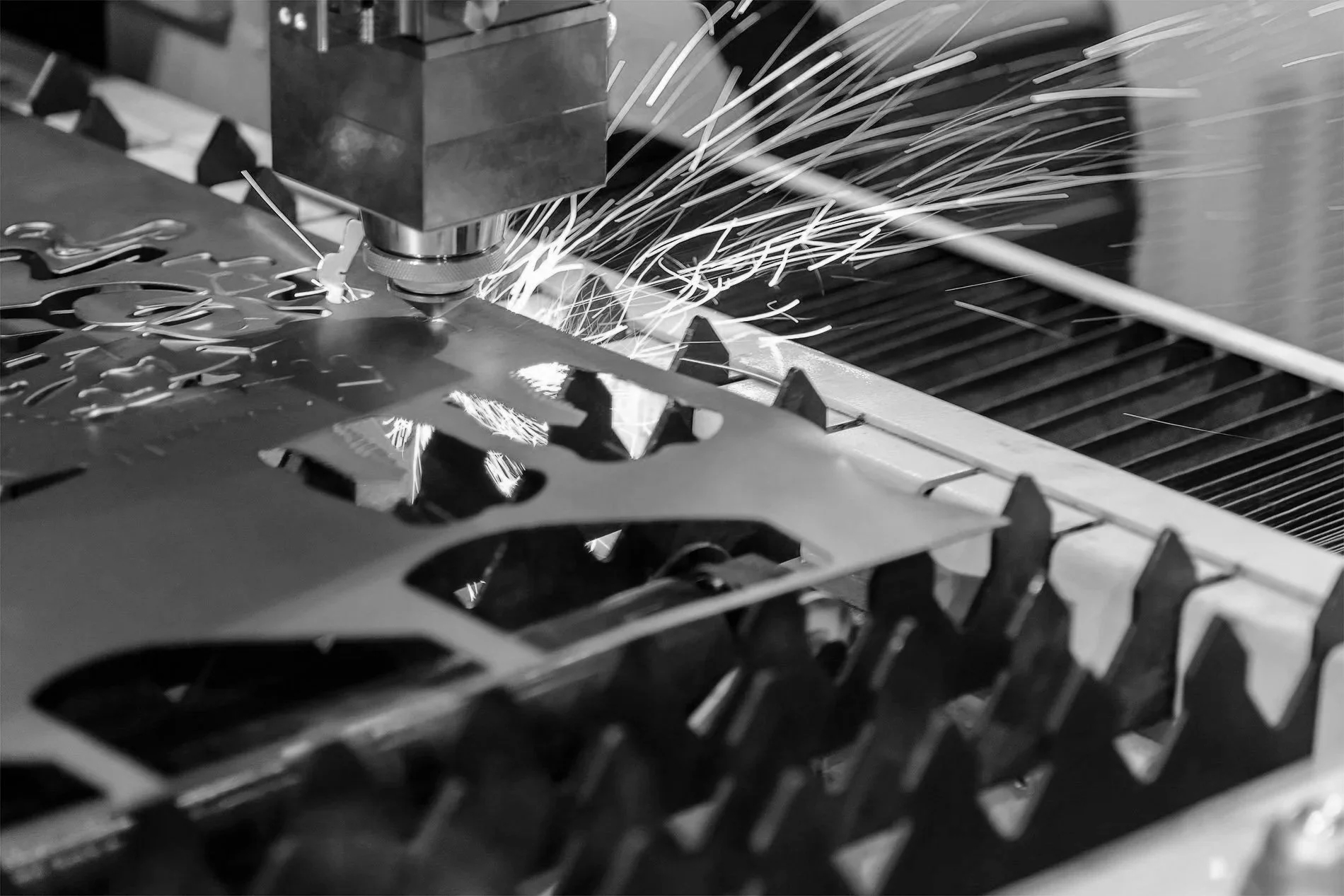 A CNC laser cutting machine cutting metal, with sparks flying during the process.