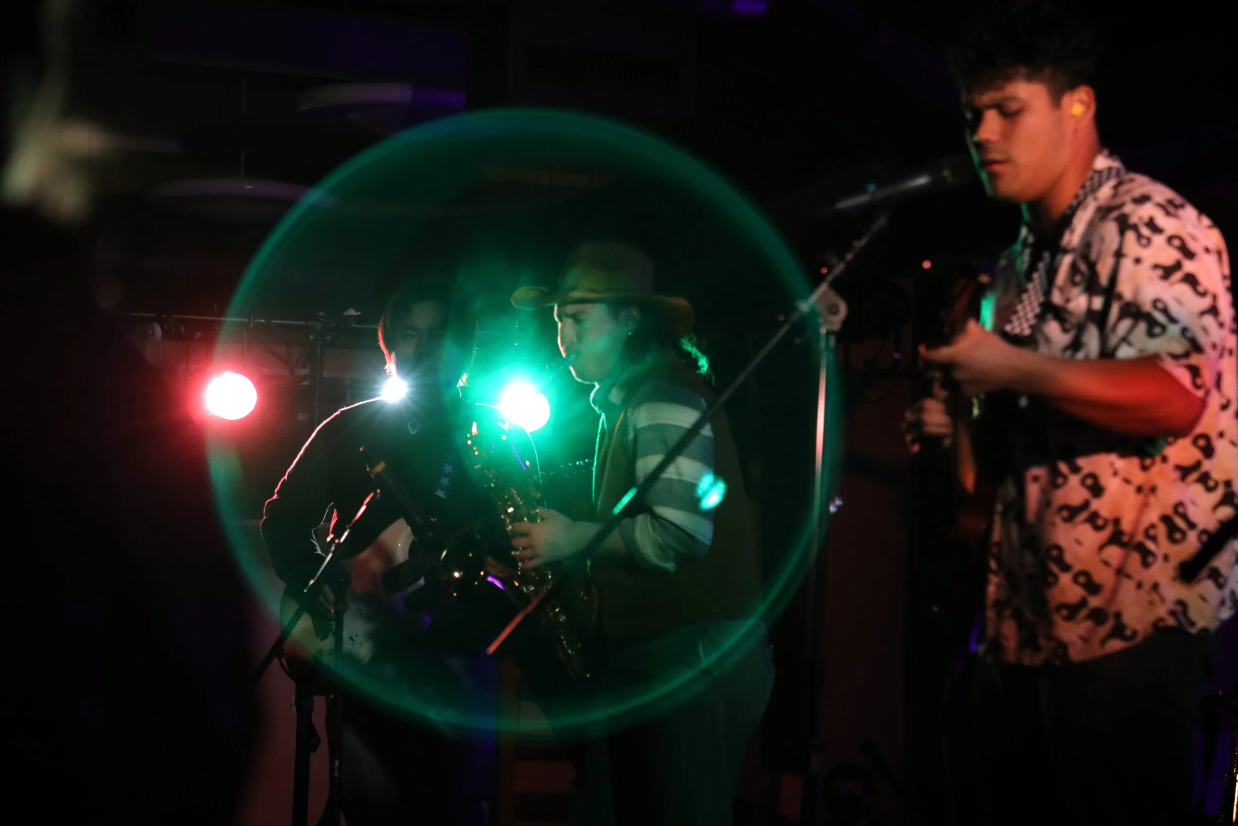 Musicians are engulfed in visual orb, created with an in-camera reflection using the light behind them during a live performance in Bellingham, Wash.