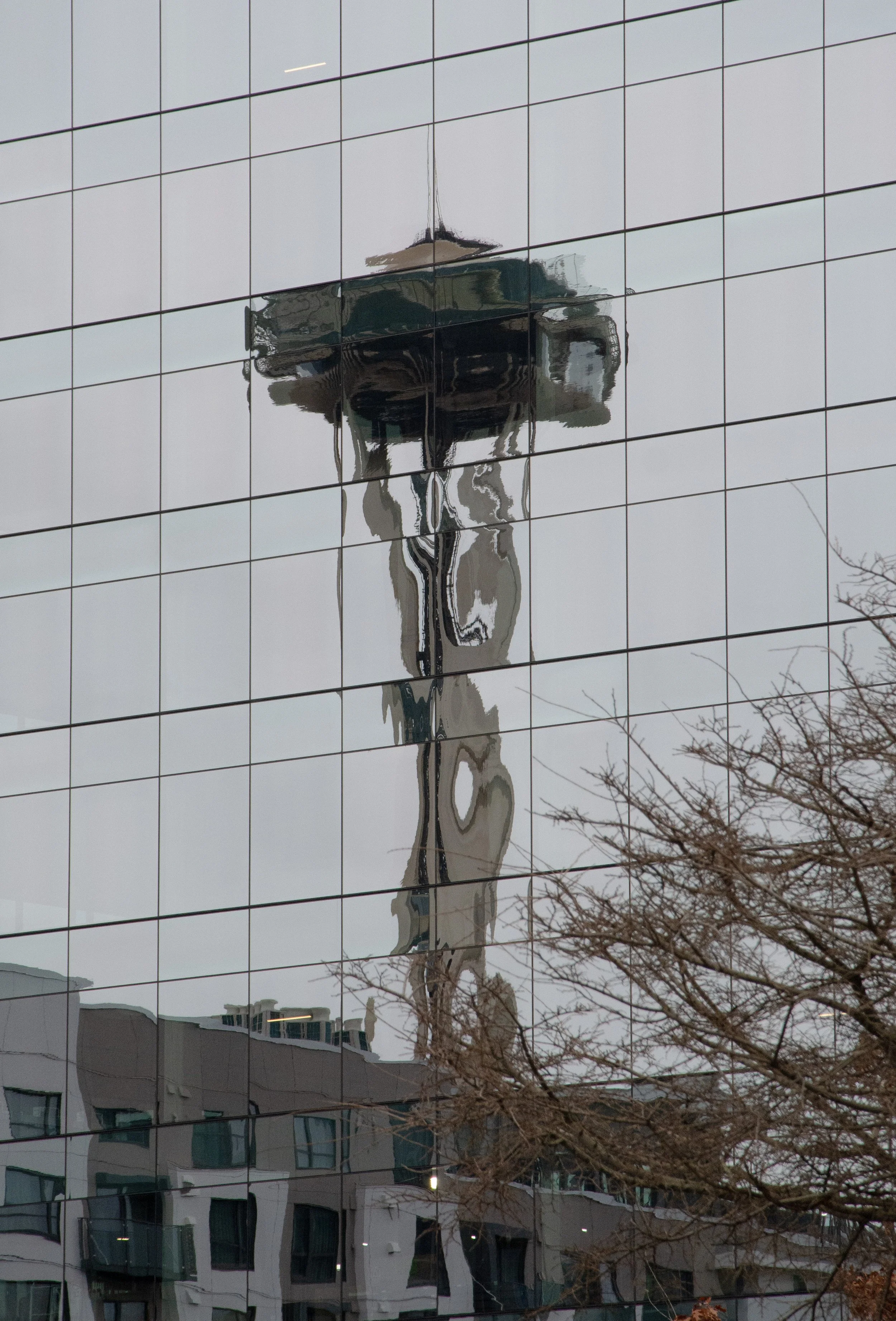 An unconventional view of the Space Needle, distorted by the glass on the side of a building in Seattle, Wash.