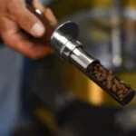 Person holding a salt shaker with pepper inside.