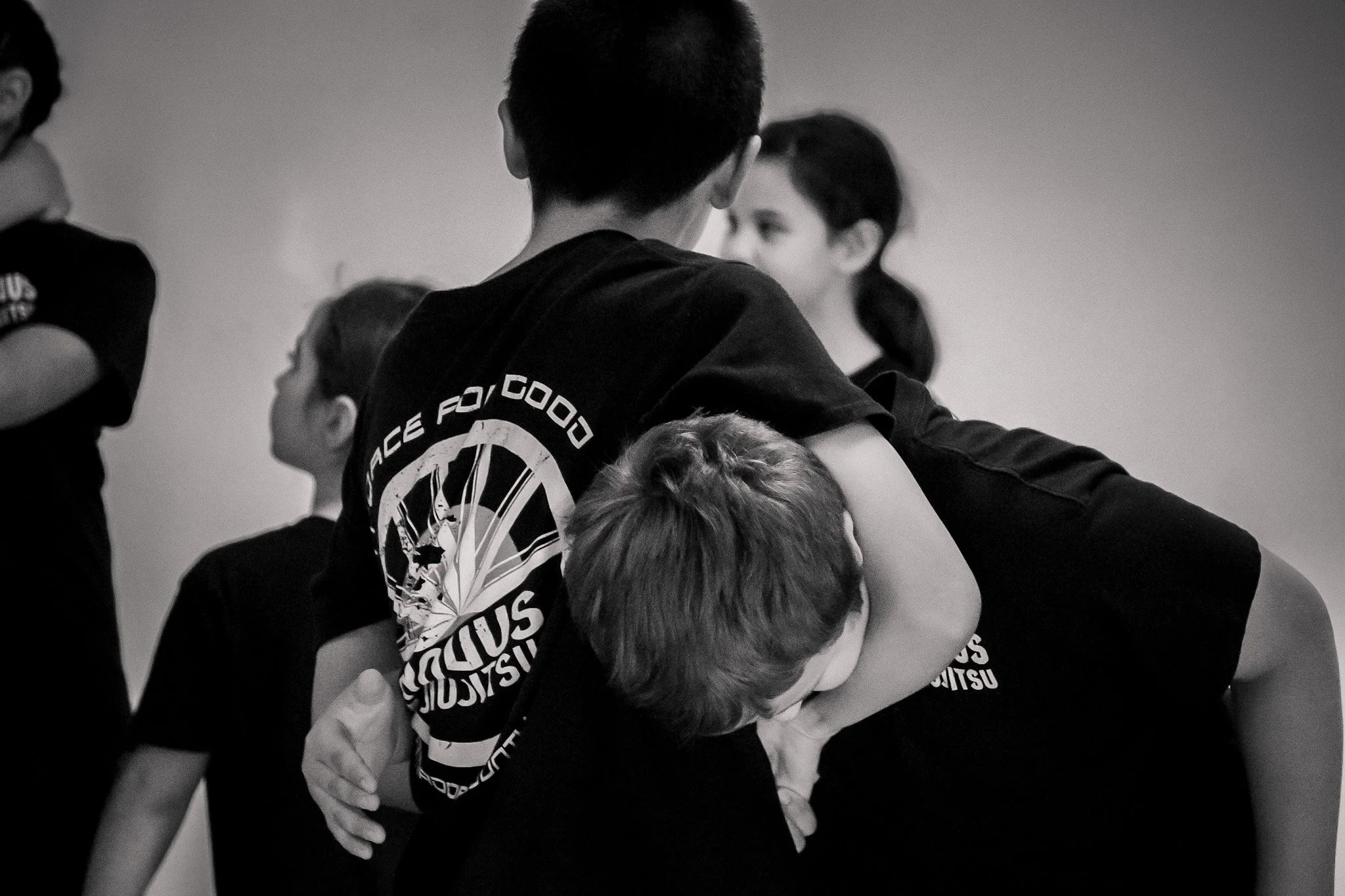 Two boys practicing grappling or wrestling, with one boy holding the other in a headlock.