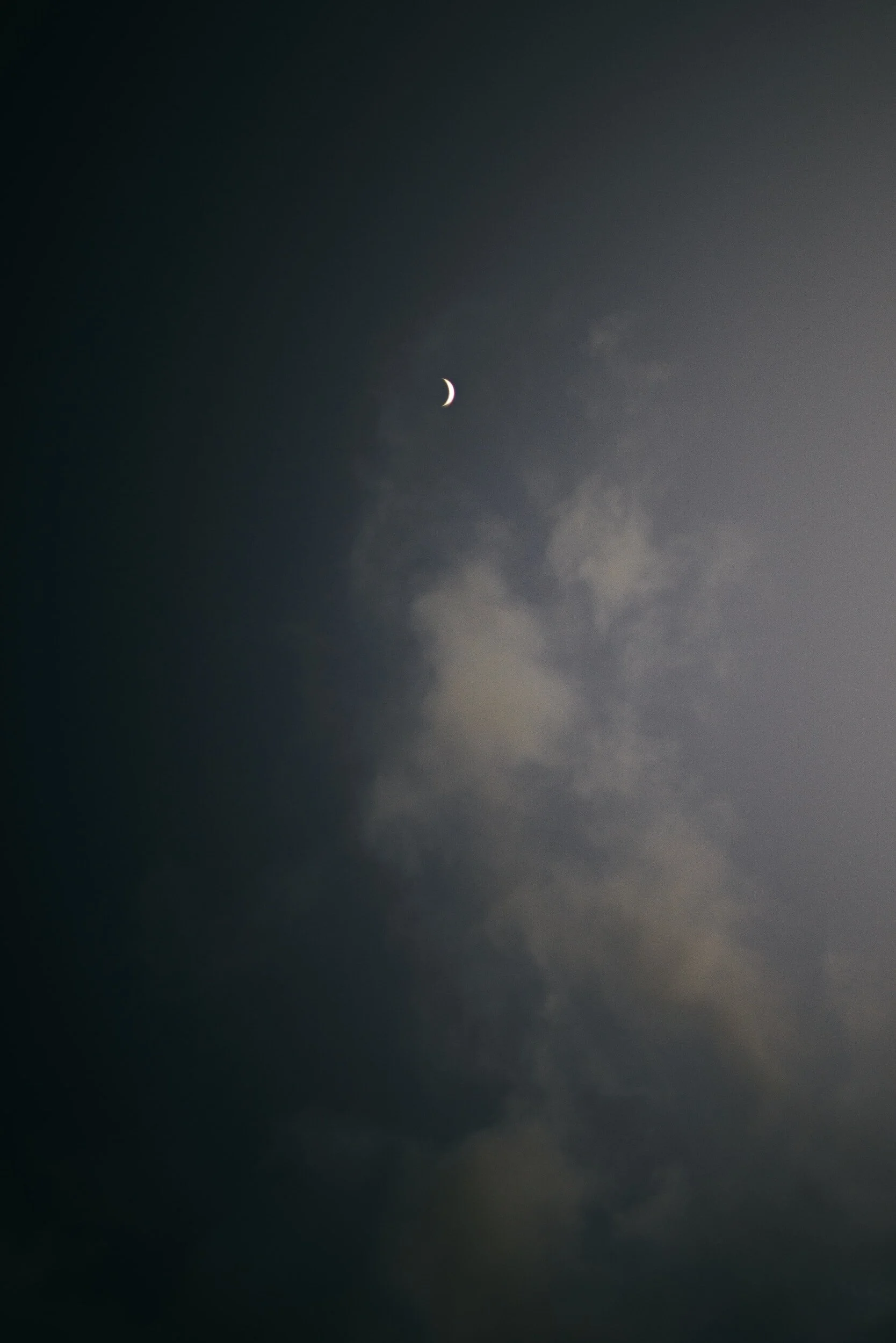 Night sky with a crescent moon and some clouds.