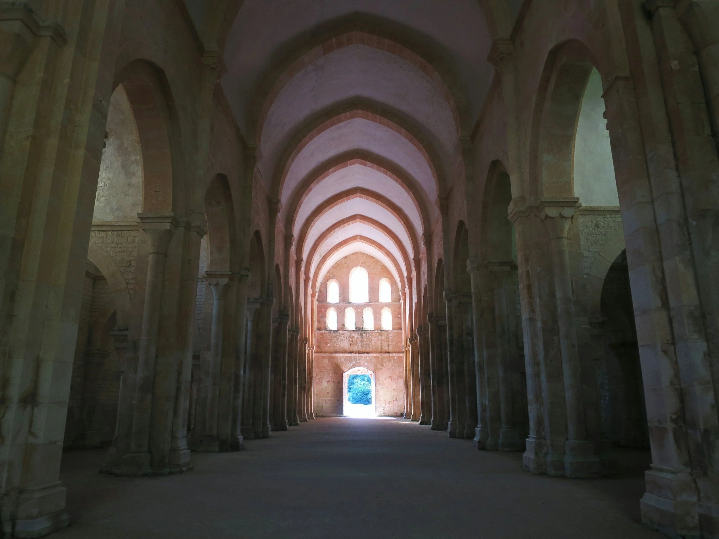 Interior of an old church with high arched ceiling, columns lining the sides, and light coming through windows at the far end.