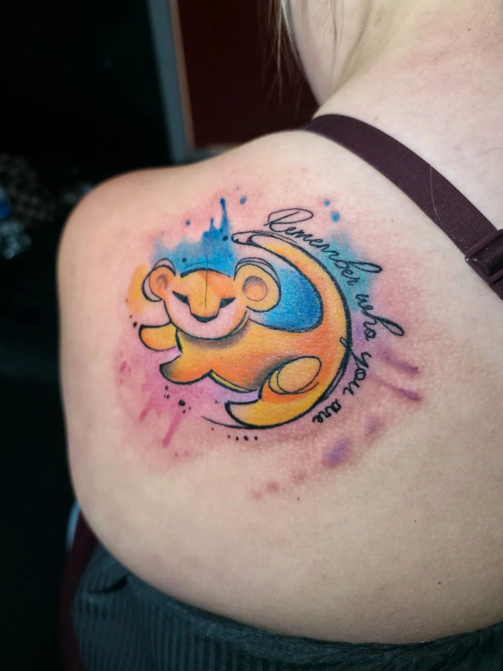 Colorful tattoo of a lion cub with the words 'Courage, Love, Hope, and Faith' around it, on a person's shoulder or upper arm.