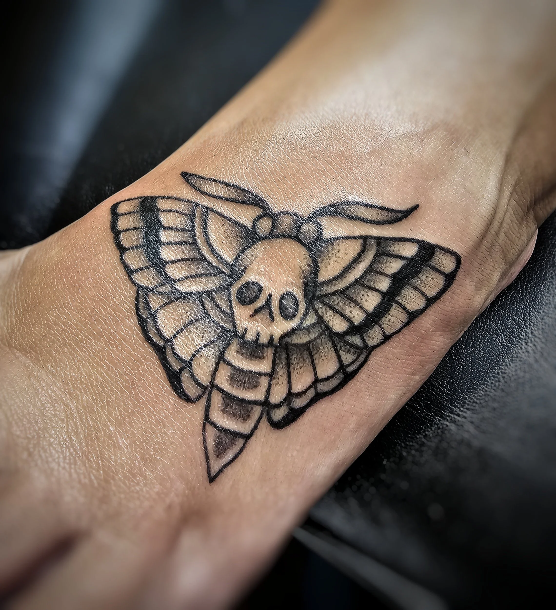 Close-up of a person's skin with a tattoo of a bee and honeycomb pattern on their arm.