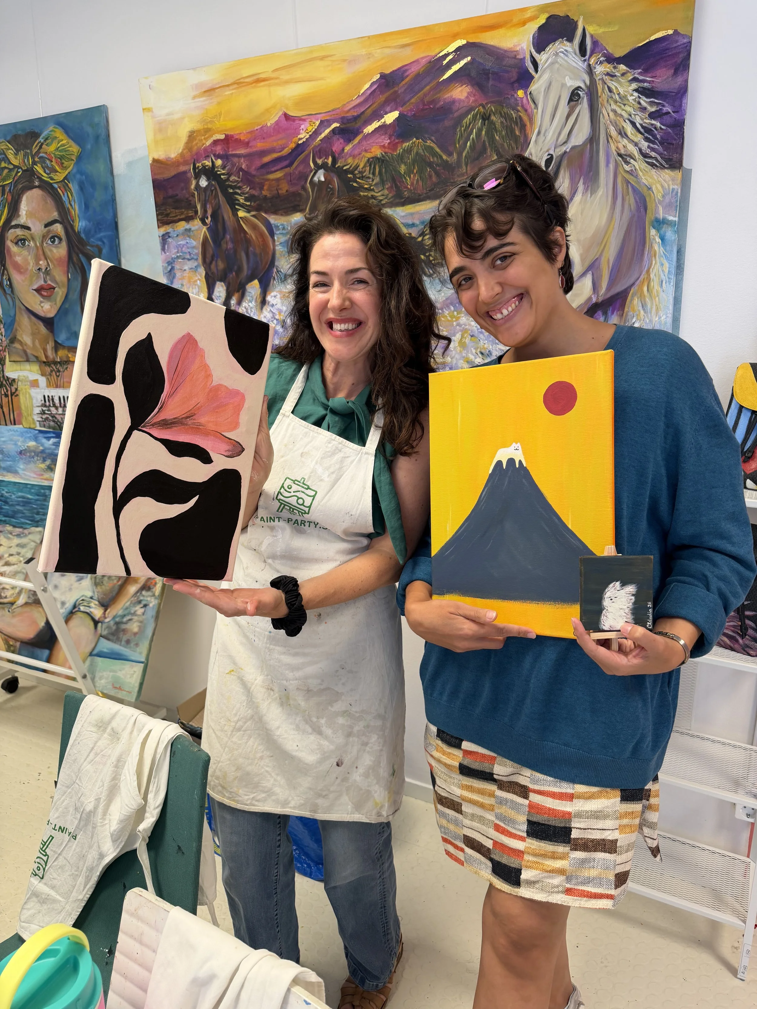 Two women smiling and holding their paintings after an Open Canvas Sunday session at the House of Mica Art Studio in Västra Hamnen, Malmö, run by contemporary artist Mica Stojanovic.